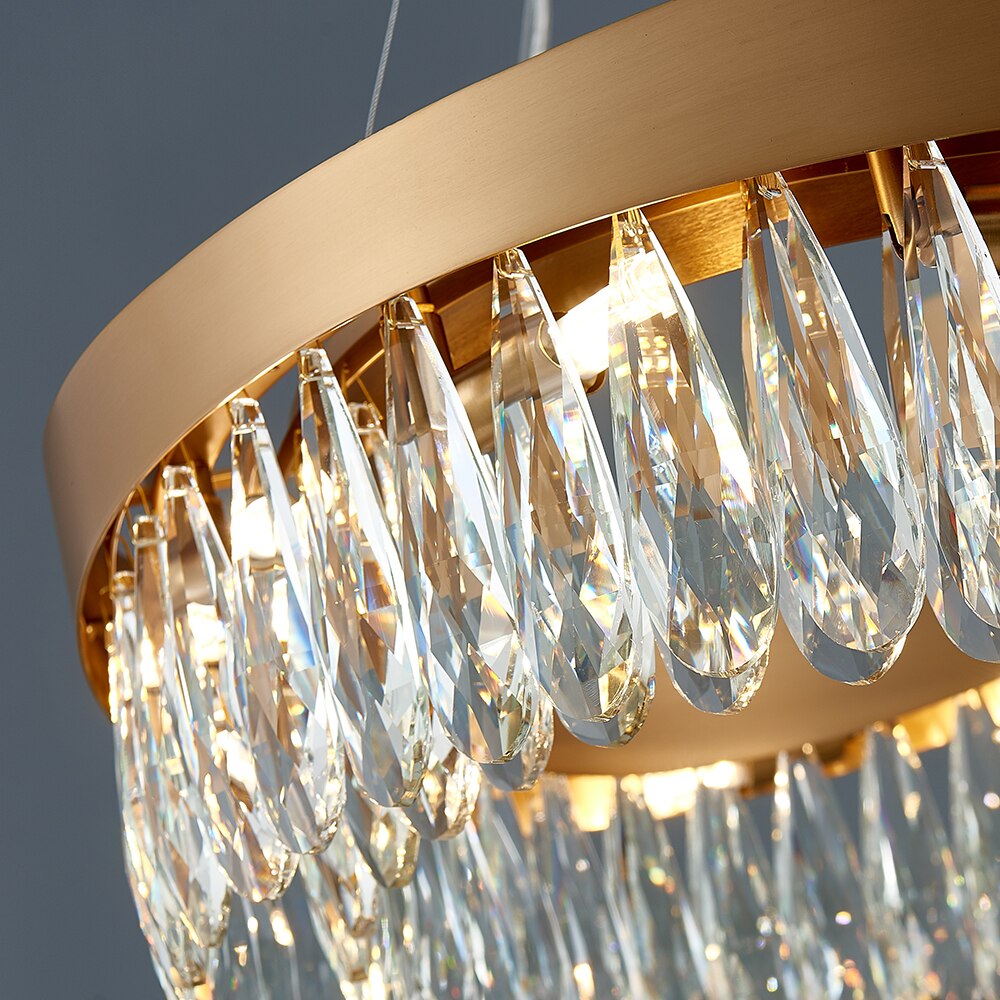 Close angled view of cascading teardrop crystals along a rectangular gold chandelier frame