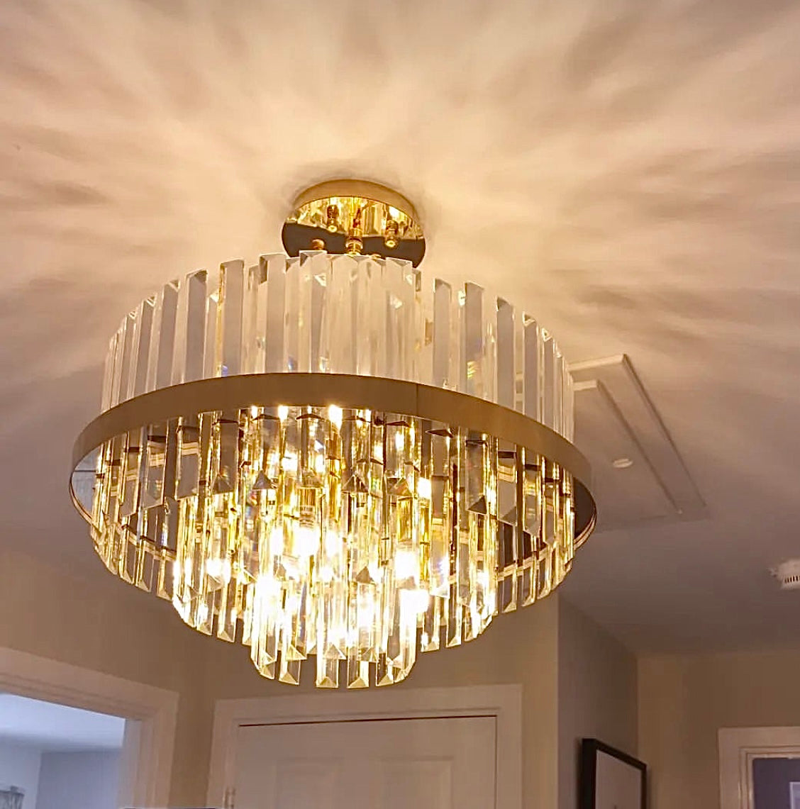 Tiered crystal chandelier creating a warm and elegant ambiance in a dining area.