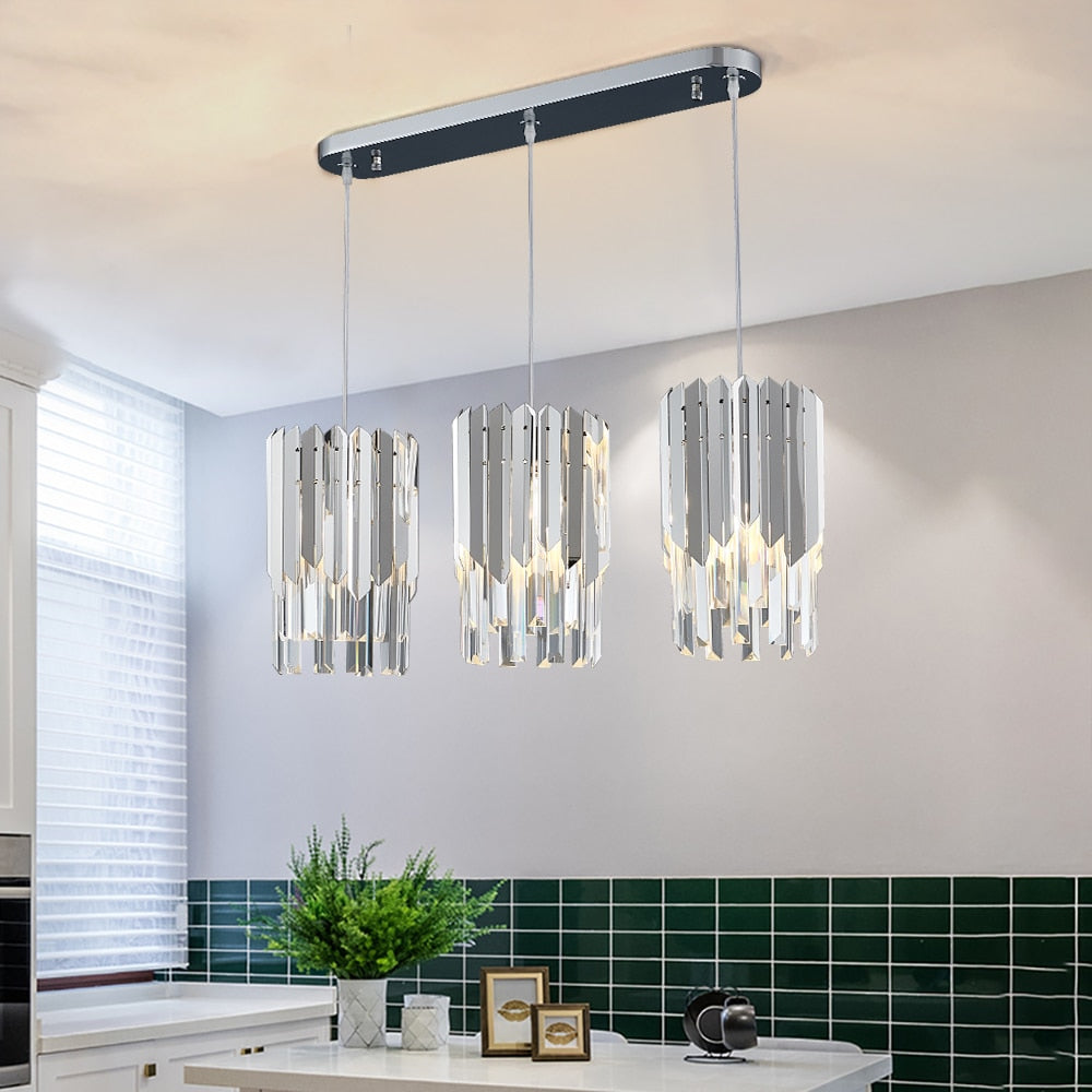 Three pendant crystal lights from the VORELLI Manhattan Rectangular Chandelier II installed above a modern kitchen island