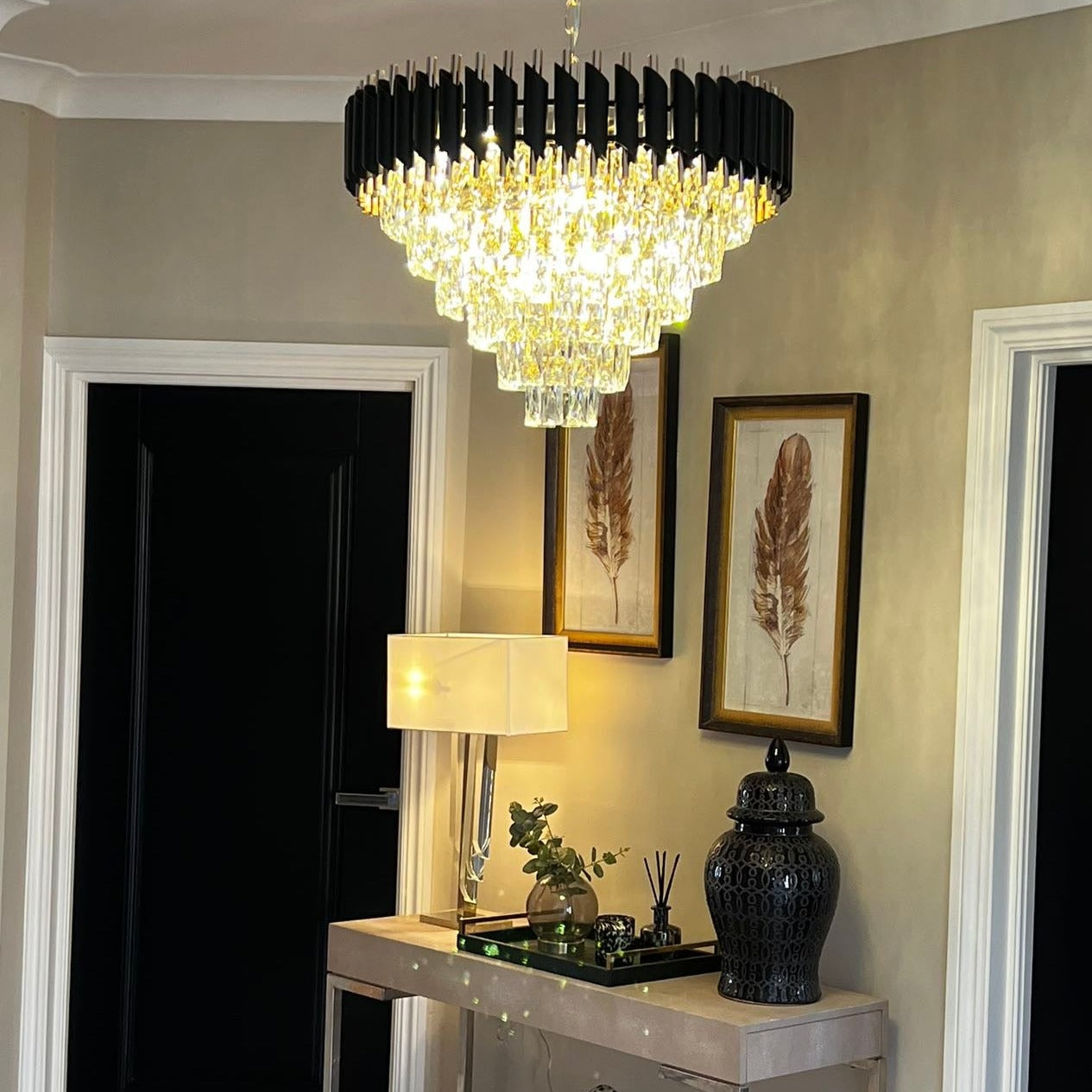 Luxury tiered crystal ceiling chandelier by VORELLI® with diamond cut faceted crystals creating a dramatic light pattern.
