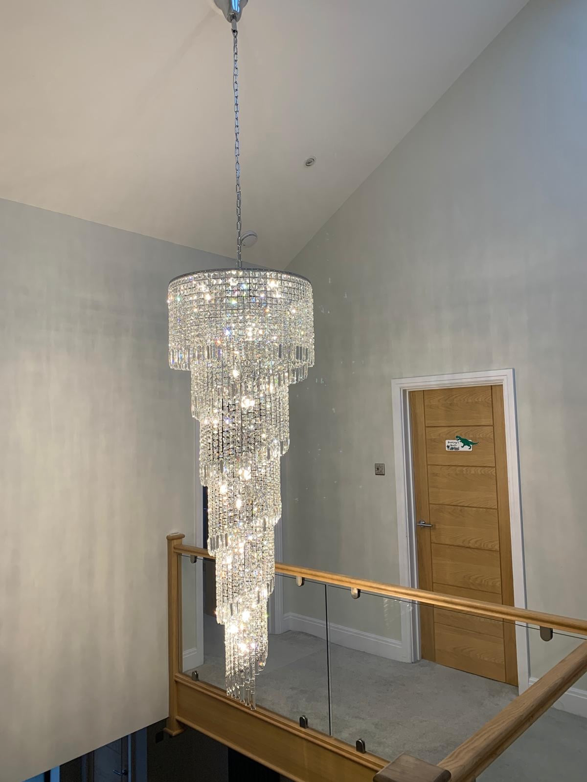 Basiglio long staircase chandelier with cascading crystal in a double height stairwell