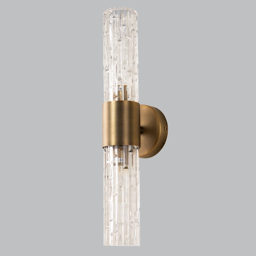 Wall-mounted light fixture with gold finish and clear glass on a gray background
