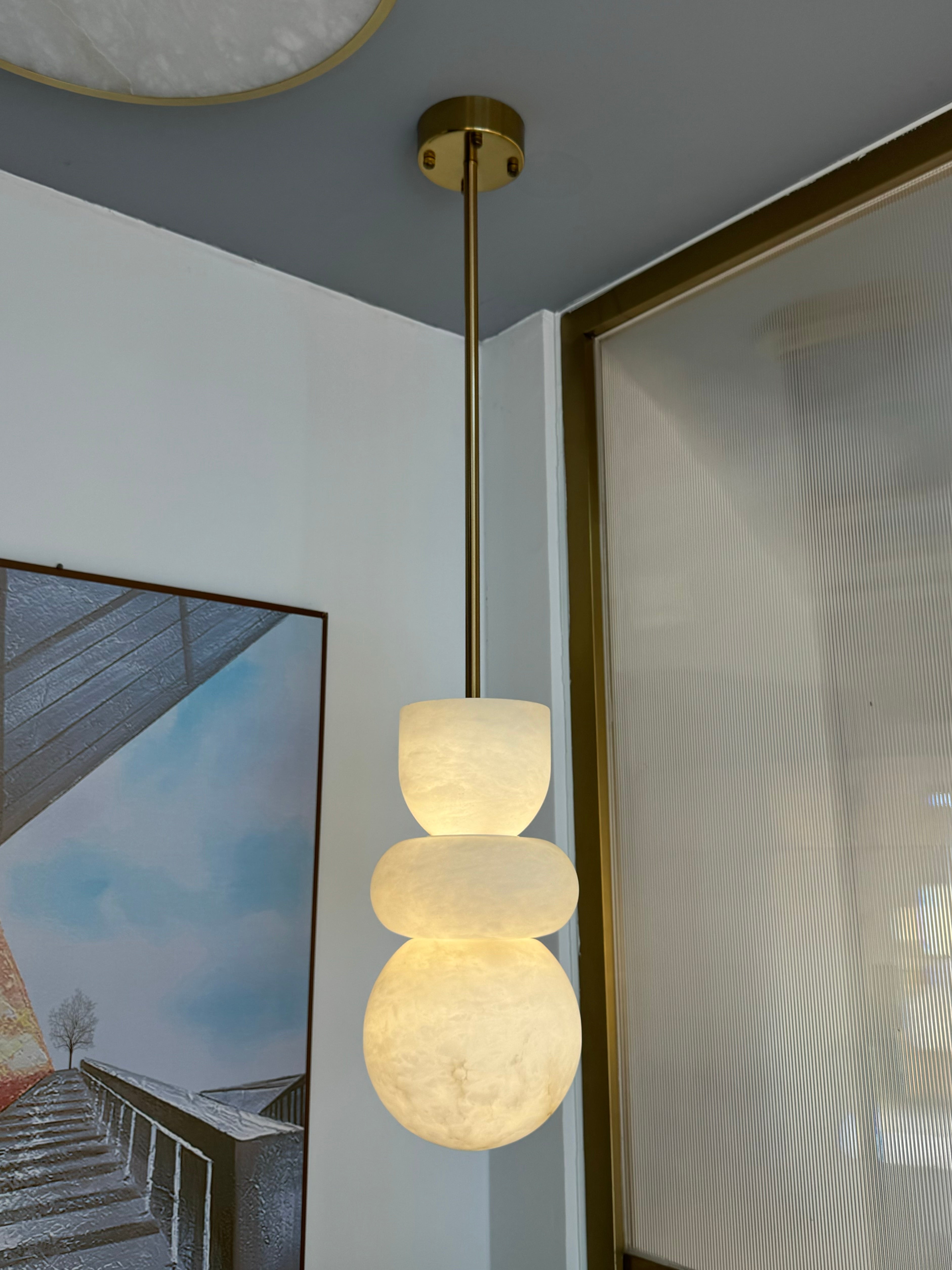 Close-up of Arco pendant light glowing warmly in a glass-panelled room.