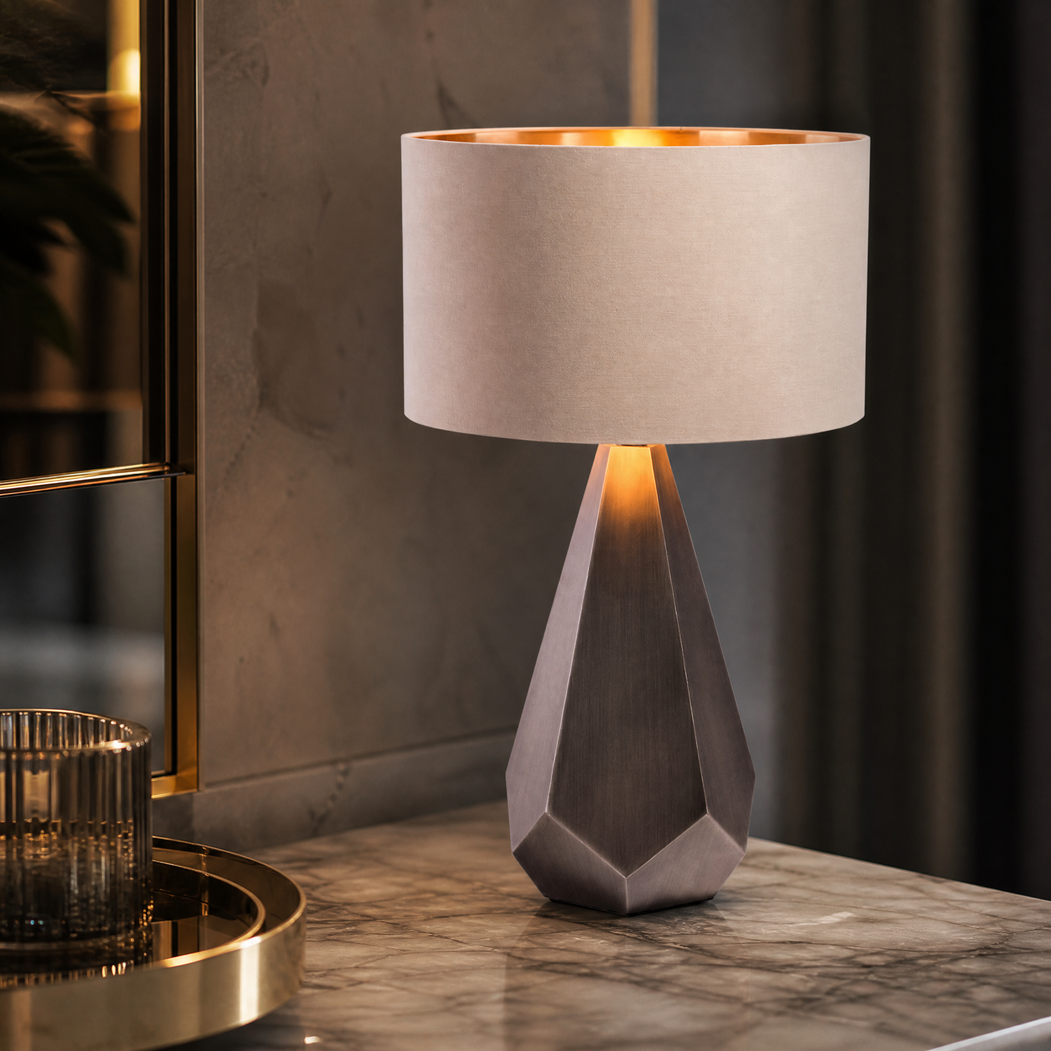 A macro close-up of the Arvion table lamp showcasing the bold geometric depth and architectural presence of its sculpted, faceted base in a brushed gunmetal finish.