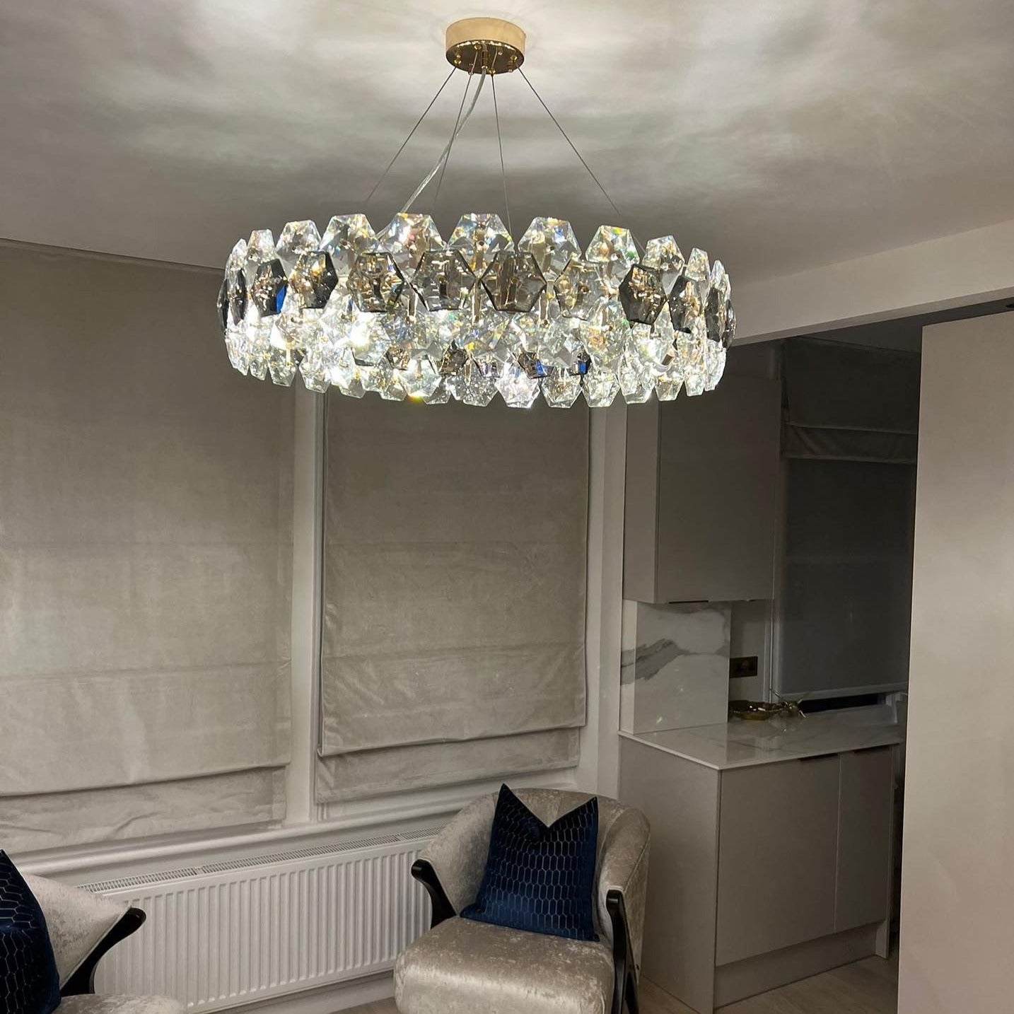 Astoria chandelier illuminating a modern living room with elegant grey and clear crystals.