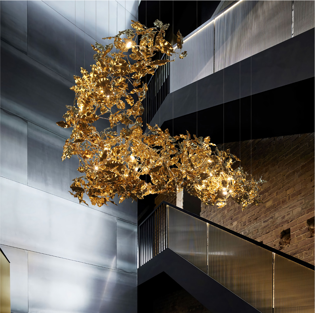 Aureus Staircase Chandelier with golden leaf elements suspended in a modern stairwell.