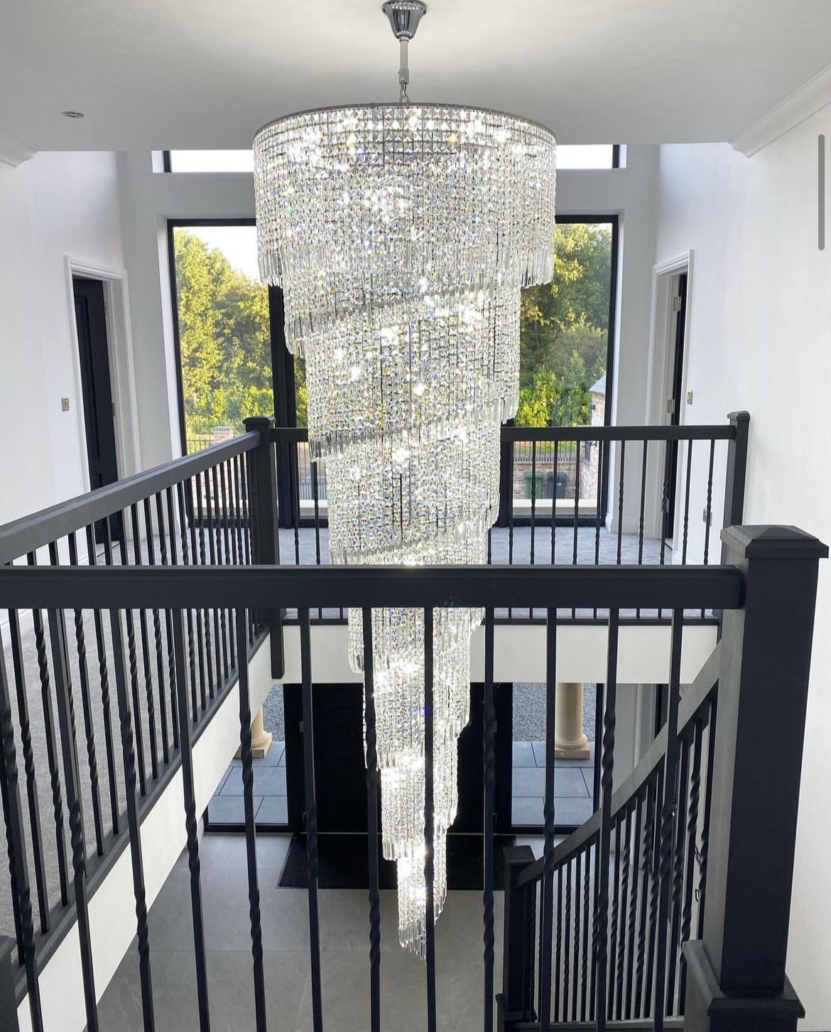 Front hallway view of the Basilgio chandelier highlighting its spiral crystal arrangement.
