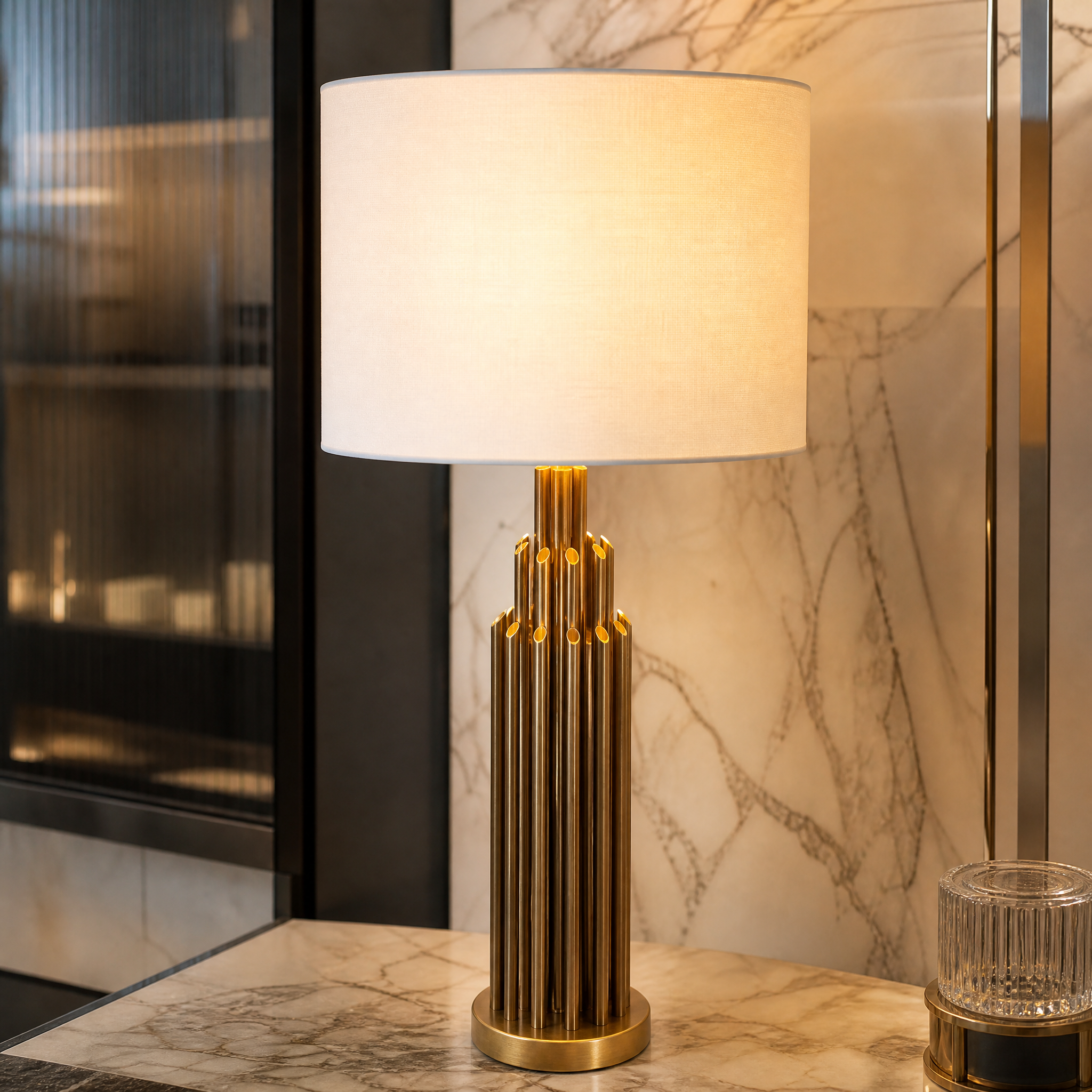 A detailed close-up showing the precise layered brass detailing and structured cylindrical base of the VORELLI Calviero table lamp.
