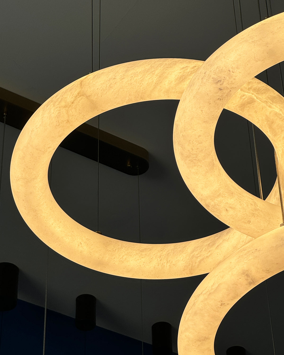 Detailed view of a marble ring on the Cavani Marble Trio Circular Chandelier showing natural veining and warm illumination.