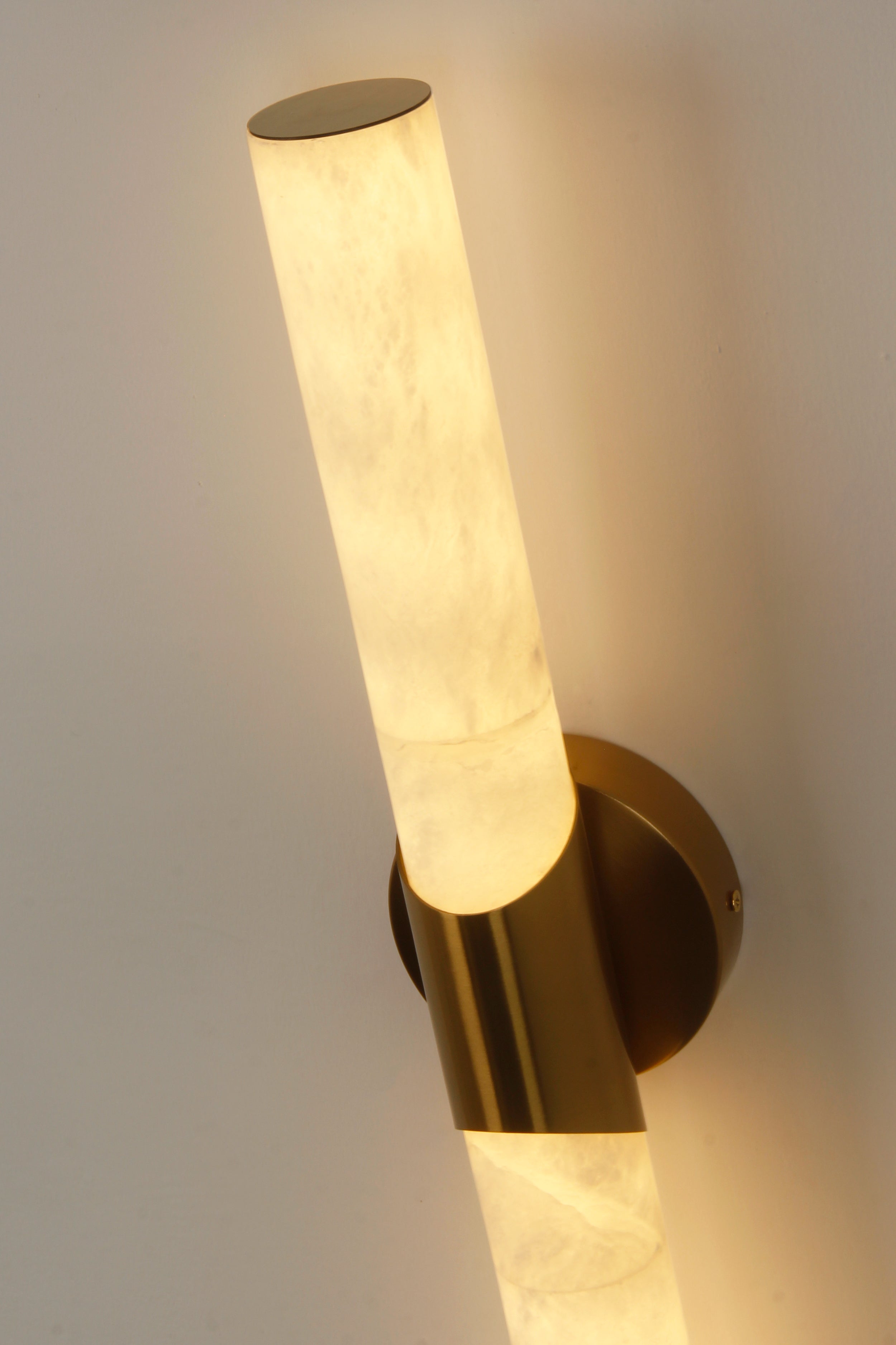 cilindro marble wall light close up showing warm illumination and brass mounting