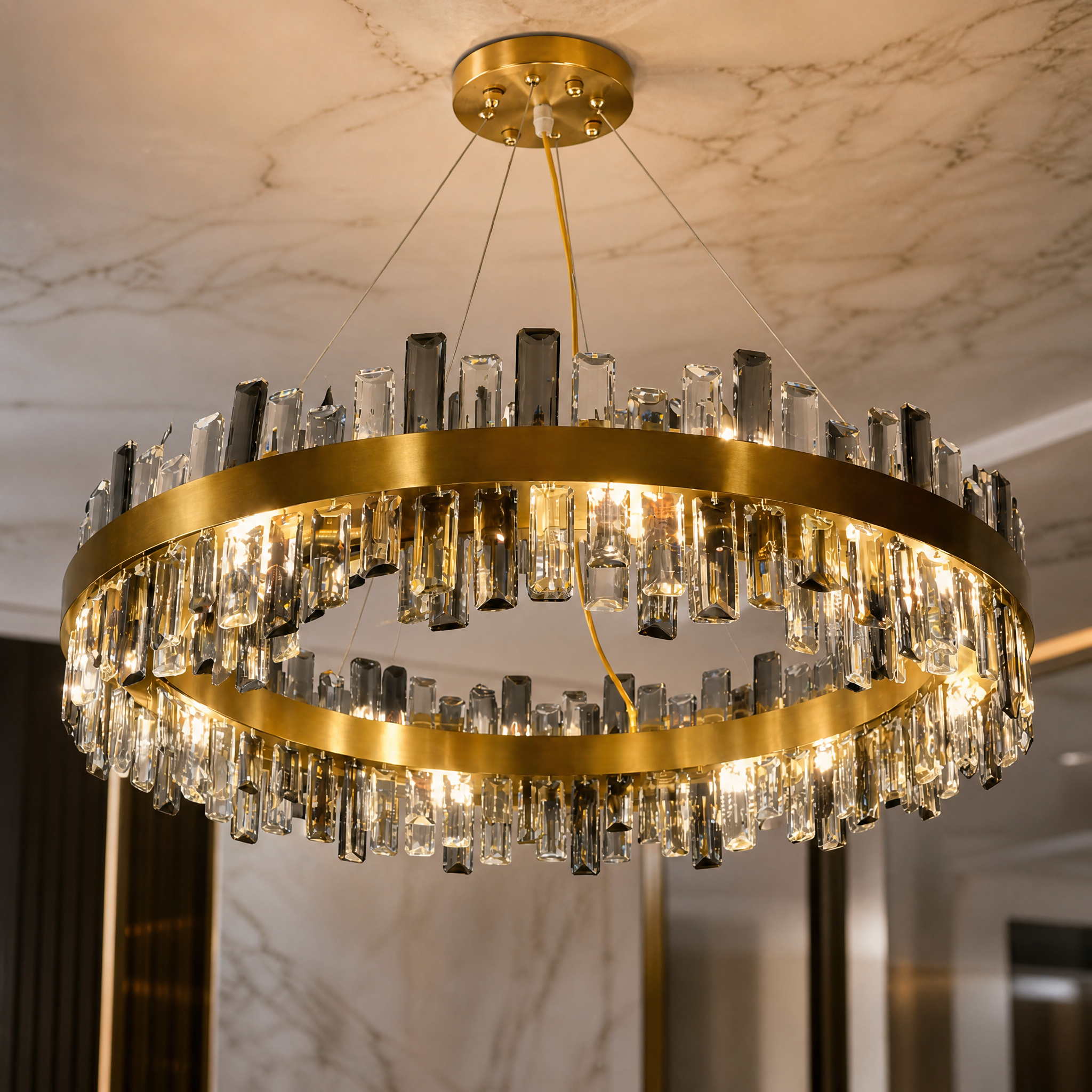 Macro close-up shot of the Figueroa chandelier's sleek stainless steel frame paired with clear and smoky grey oblong diamond cut crystals.
