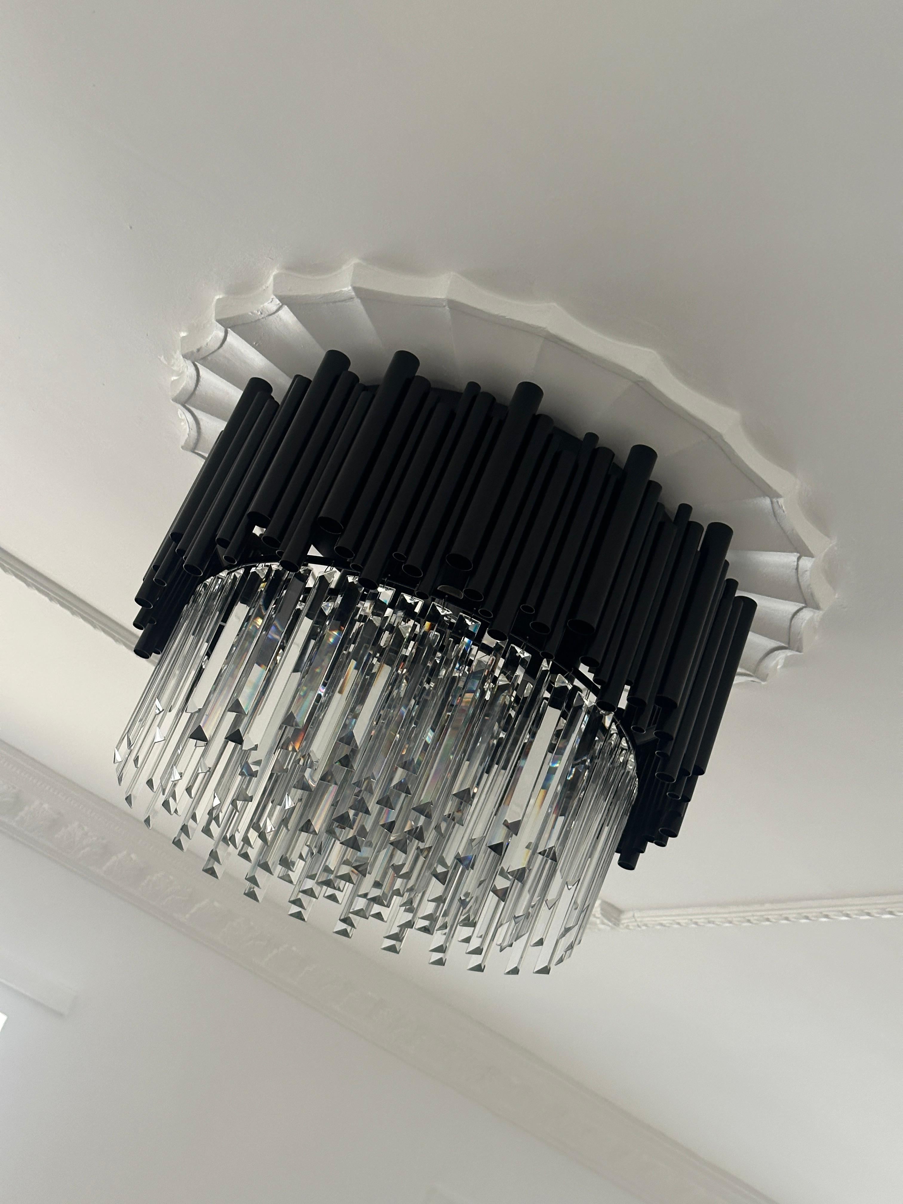Luxury Gotham ceiling light featuring black vertical rods and cascading crystal prisms in a modern interior.