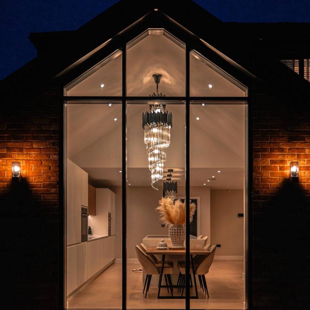 Luxury crystal staircase chandelier illuminated at dusk in modern home