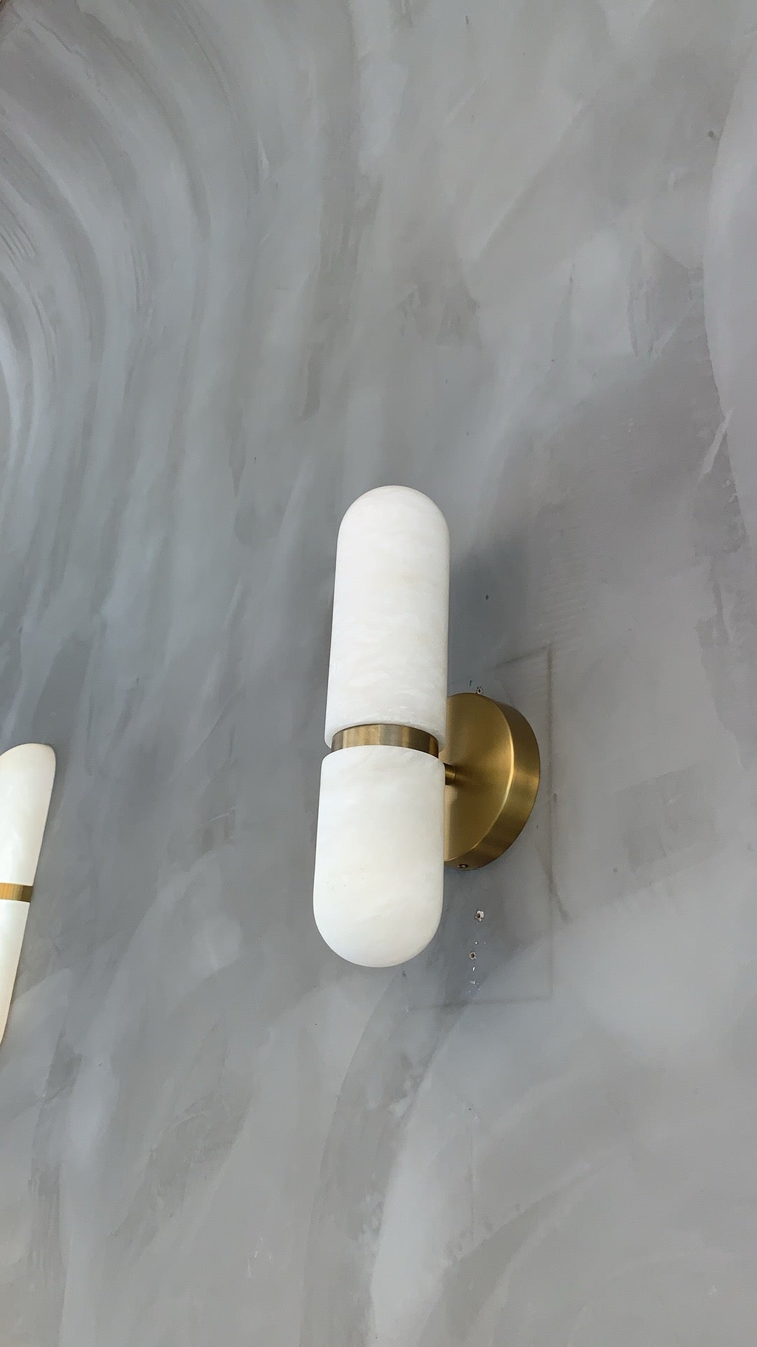 Side profile of sculpted marble shade and brass mount on Luma wall light