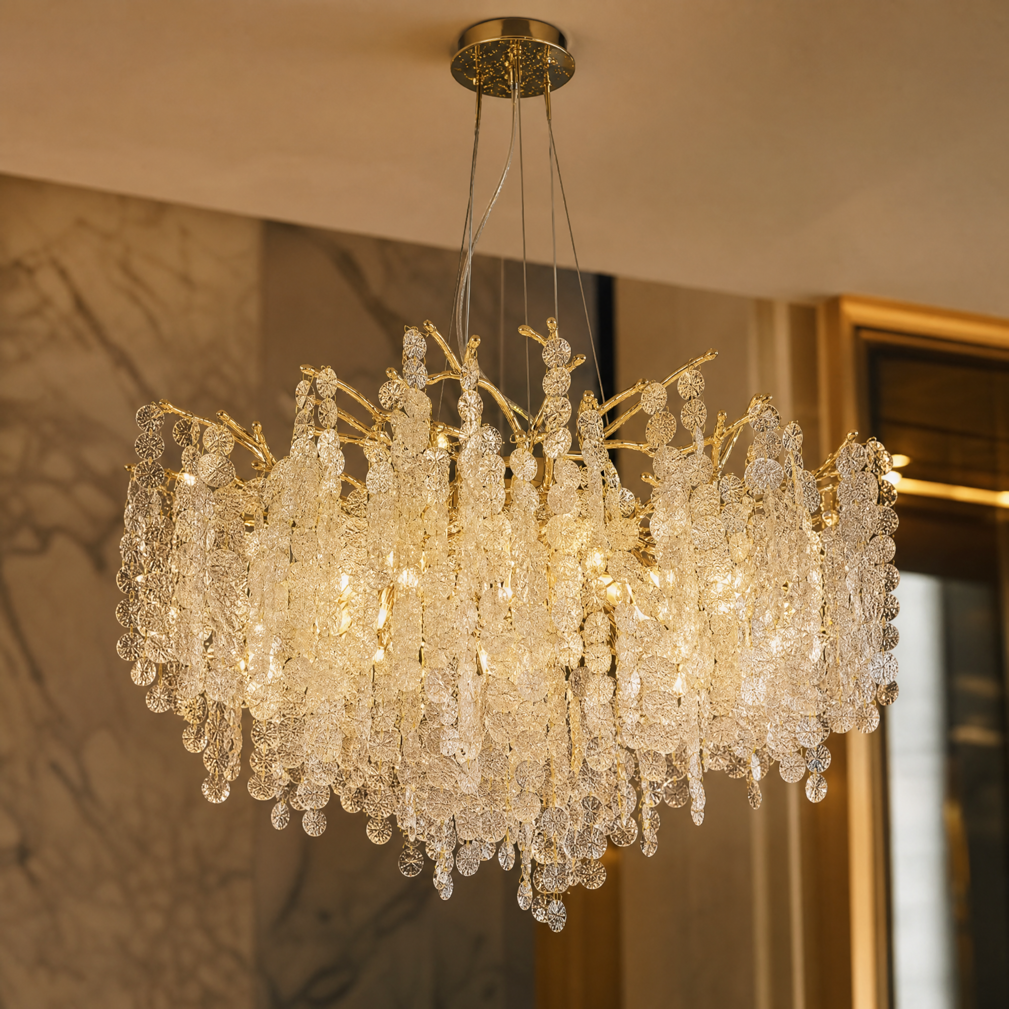 Detailed closeup of the hand-textured crystal discs and sculptural golden branch finish of the VORELLI Lunaria chandelier.