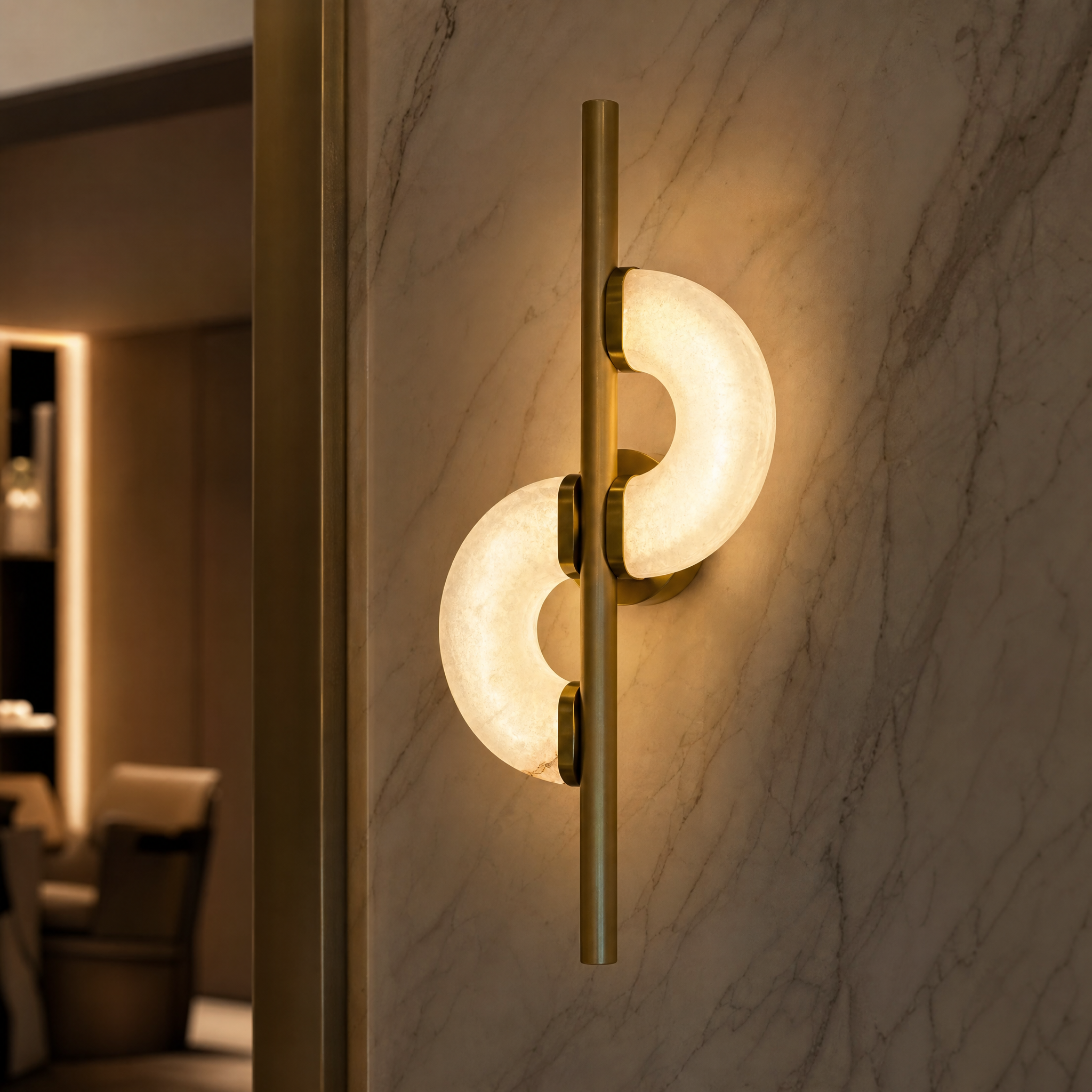 Macro closeup of the Lunaro wall light by Vorelli, highlighting the natural stone texture of the twin crescent marble forms and the vertical brushed brass frame.