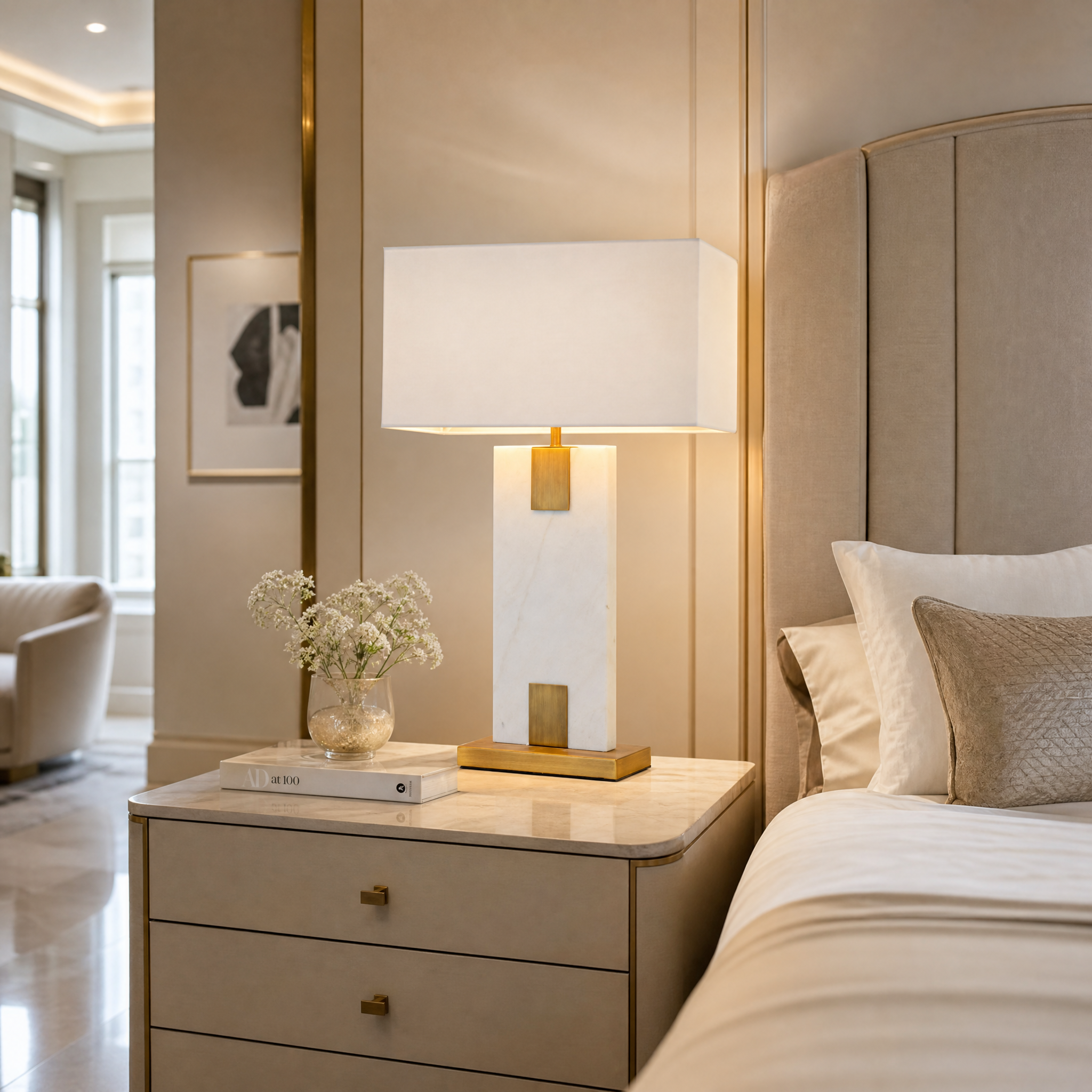 Navaro white marble and antique brass table lamp providing warm ambient illumination on a contemporary bedroom bedside table.