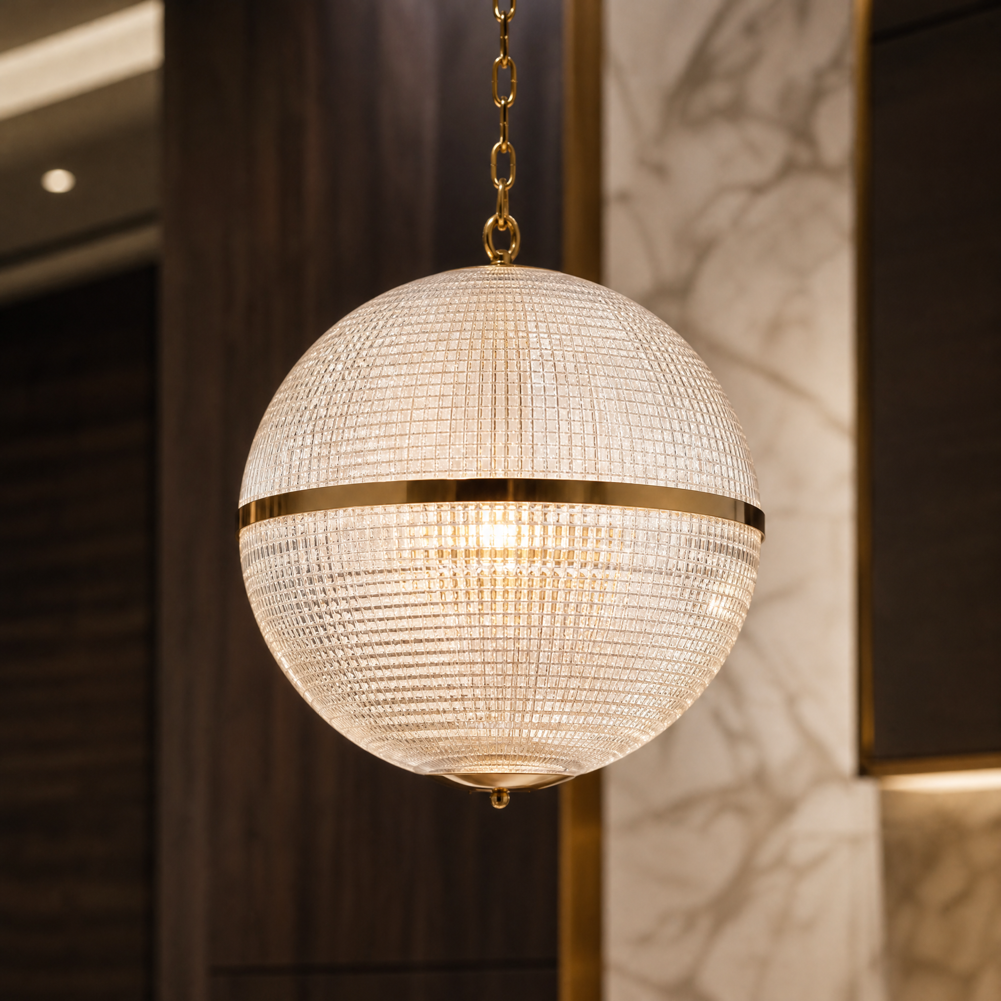 Close-up detail of the VORELLI Parigino pendant light, showcasing the textured prismatic moulded glass globe and premium brass hardware.
