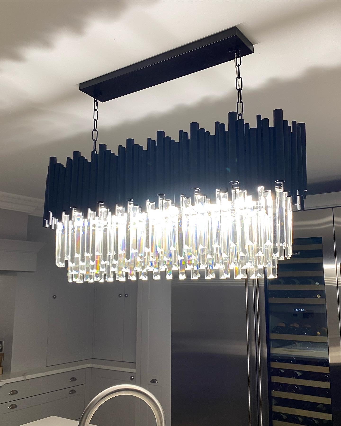 Luxury rectangular chandelier above modern kitchen island with crystal prisms