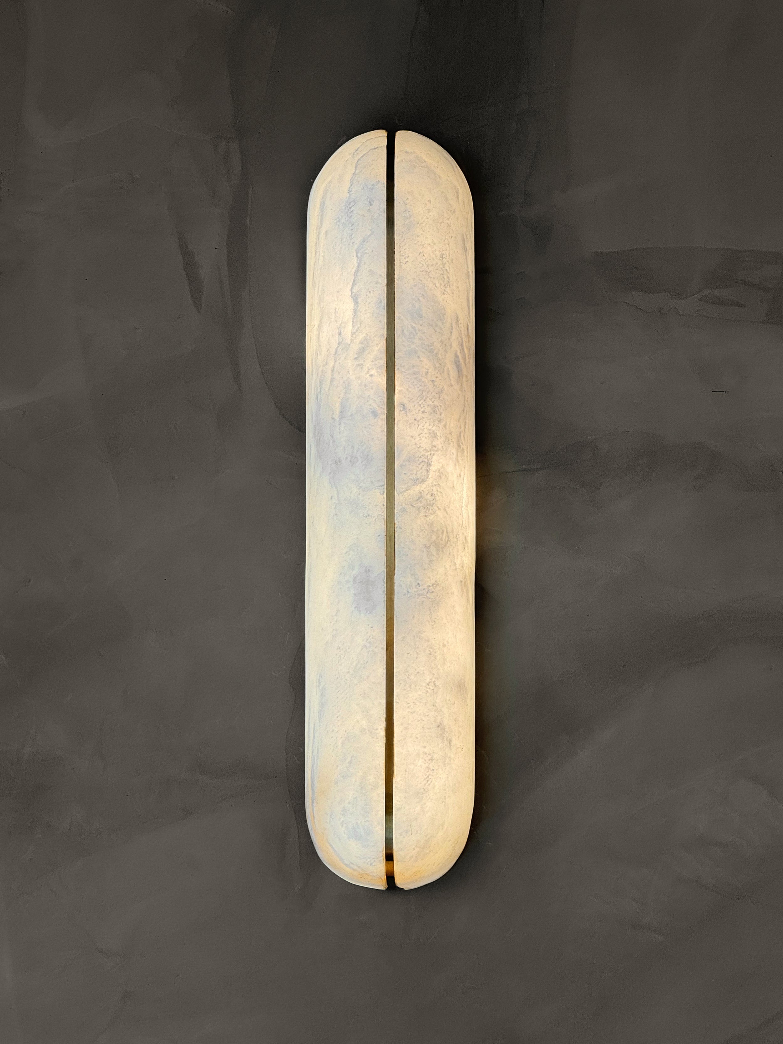 Serino modern vertical marble wall sconce installed in contemporary interior creating soft ambient glow