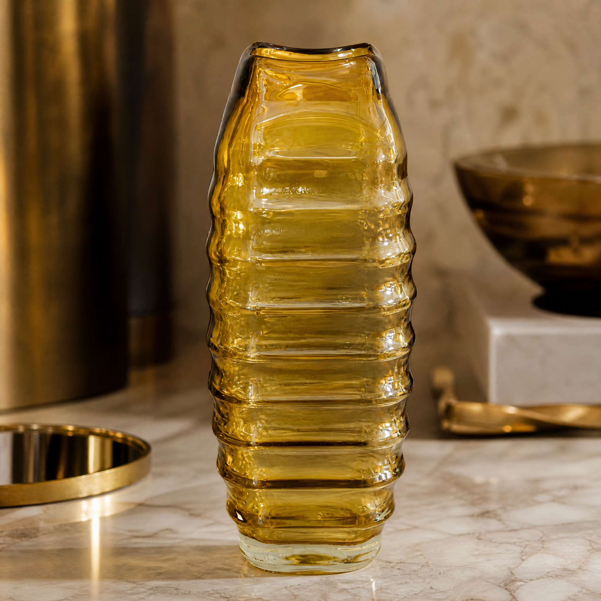 Soft ambient lighting reflecting off the ribbed yellow glass of the Valdese small vase on a wooden shelf.