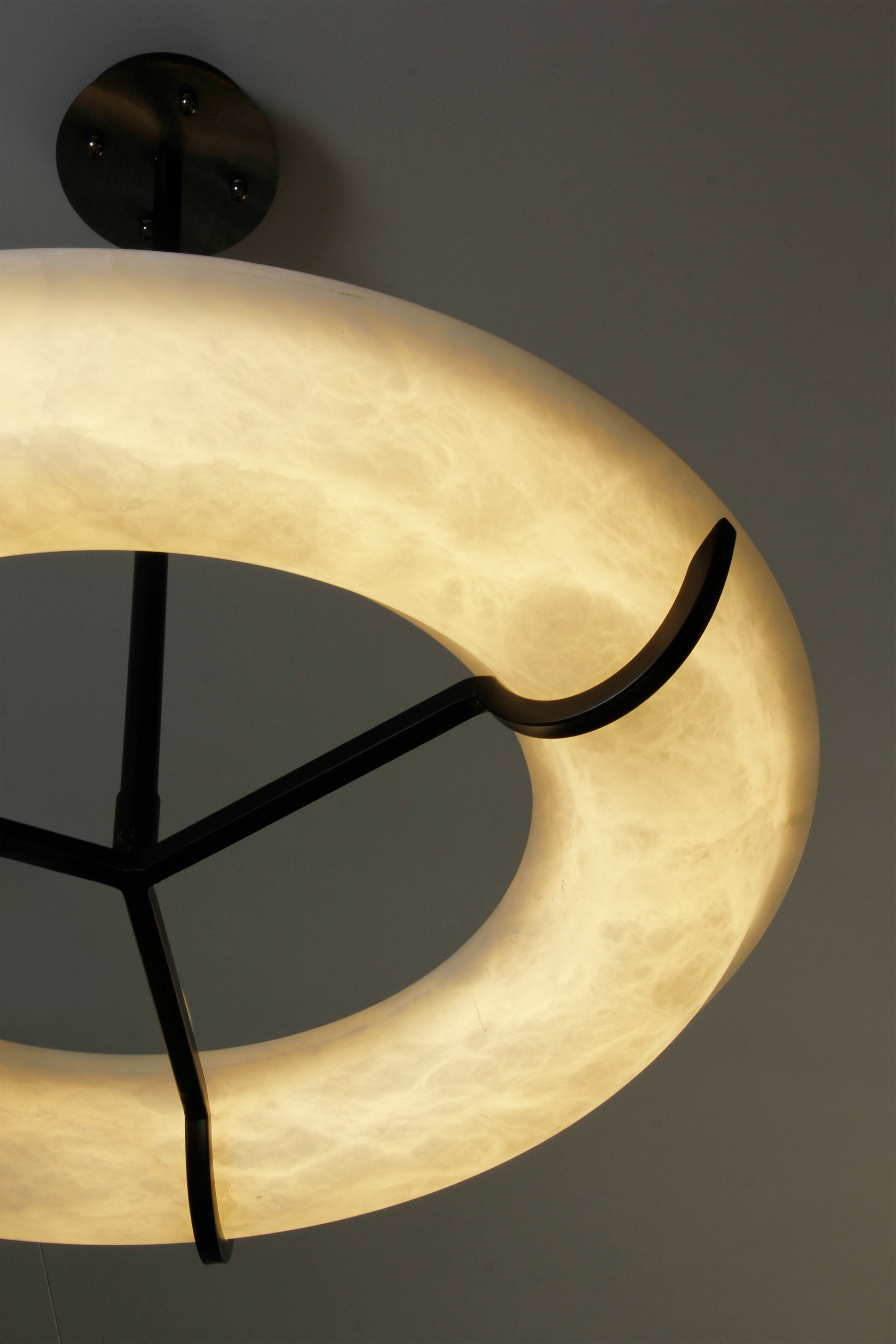 Close up of smooth marble halo and contrasting structural frame on Sorano chandelier