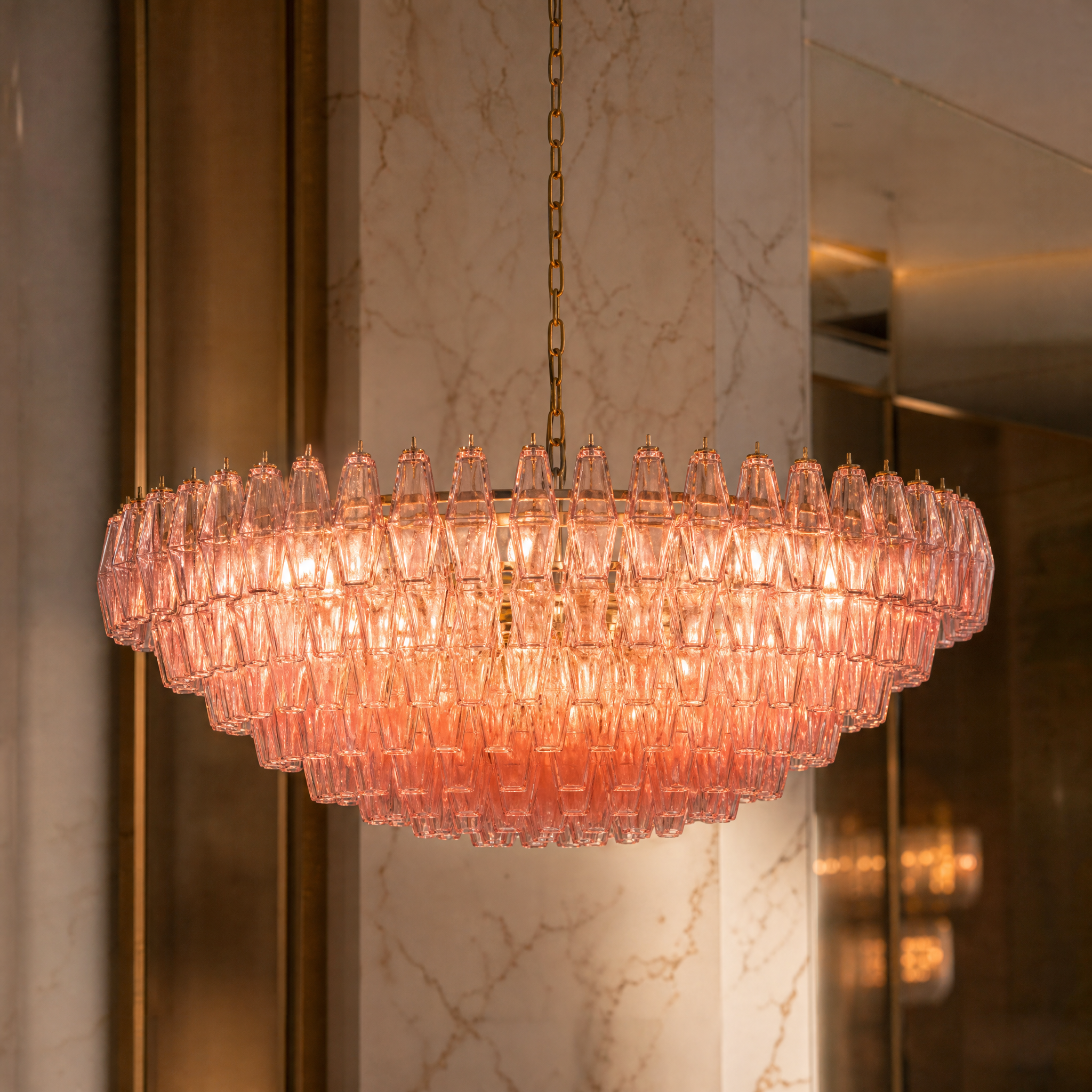 Macro shot of pink glass polyhedrons bolted to a brass frame on the Sorrentino chandelier.