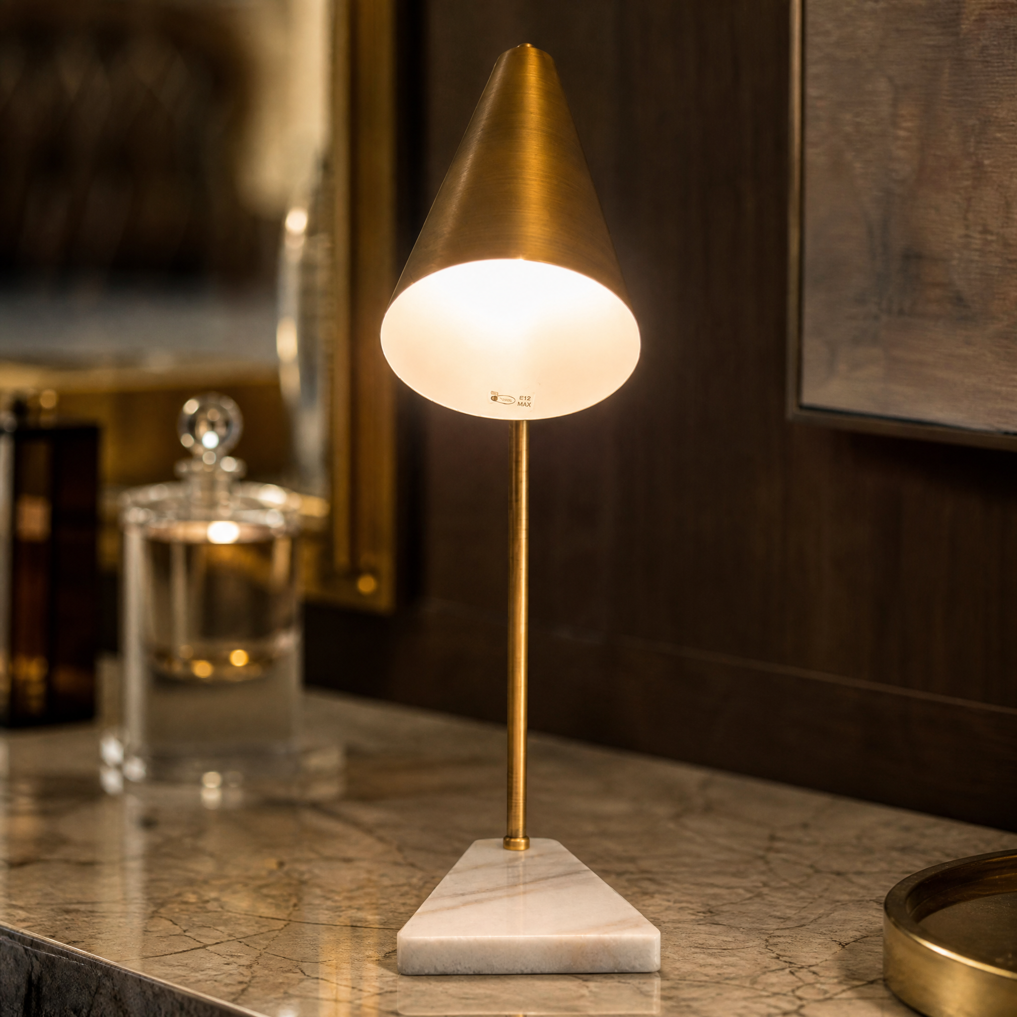 Macro shot of the VORELLI Strava table lamp showing the rich texture of the antique brass adjustable head and the solid marble base.