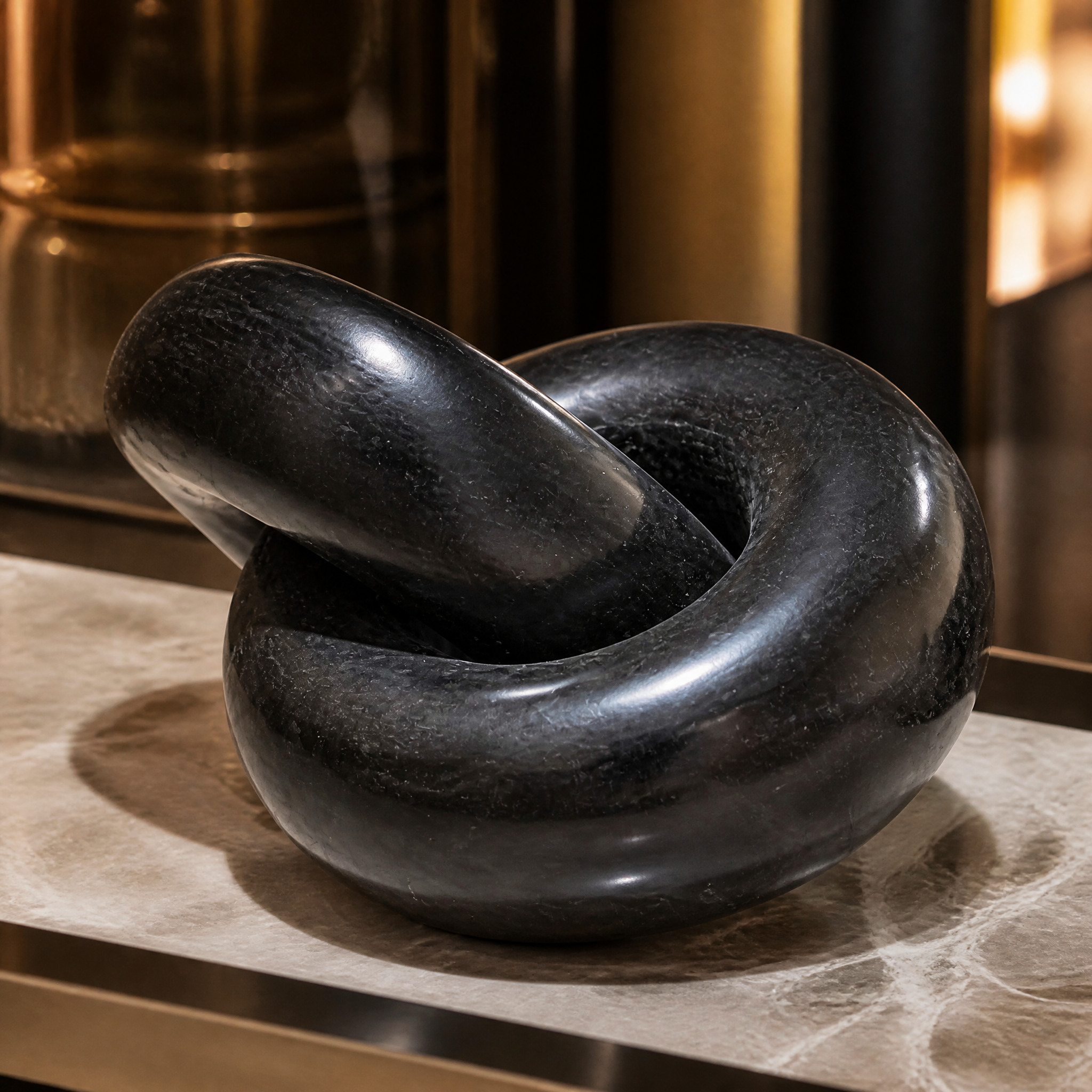 A detailed closeup of the Torrino Black Link Decor, highlighting the rich black stone, high-polished finish, and delicate natural veining of the interlocking marble knots.