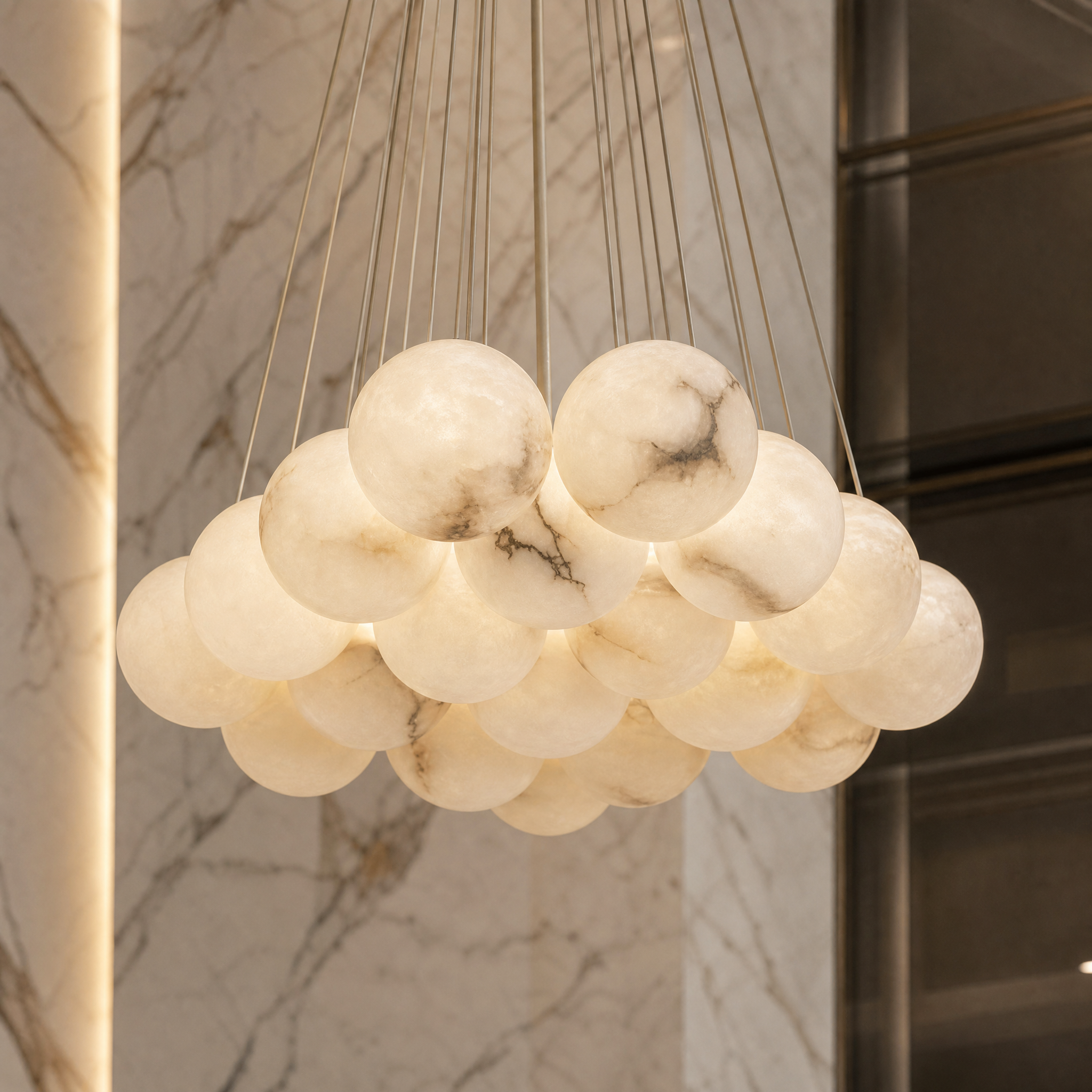 A detailed closeup of the VORELLI Valcino circular chandelier, highlighting the texture of an illuminated alabaster ball against the premium bronze frame.