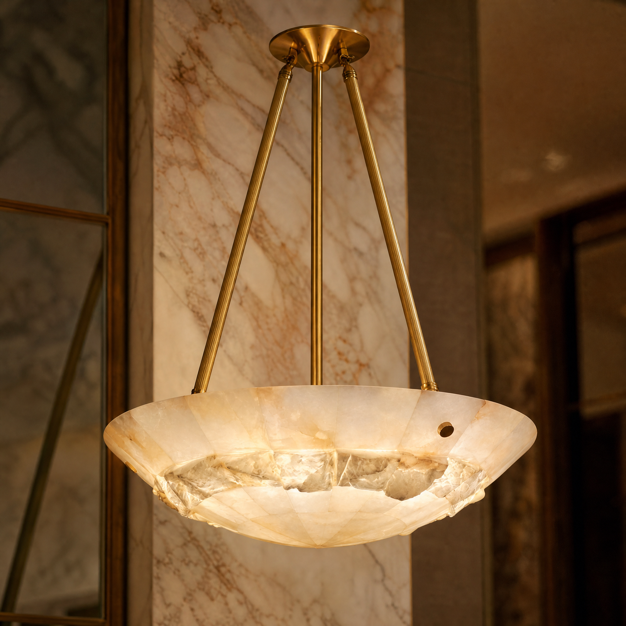 A close-up shot showcasing the natural translucent texture of the Valleria circular marble chandelier and its sleek brass supports.