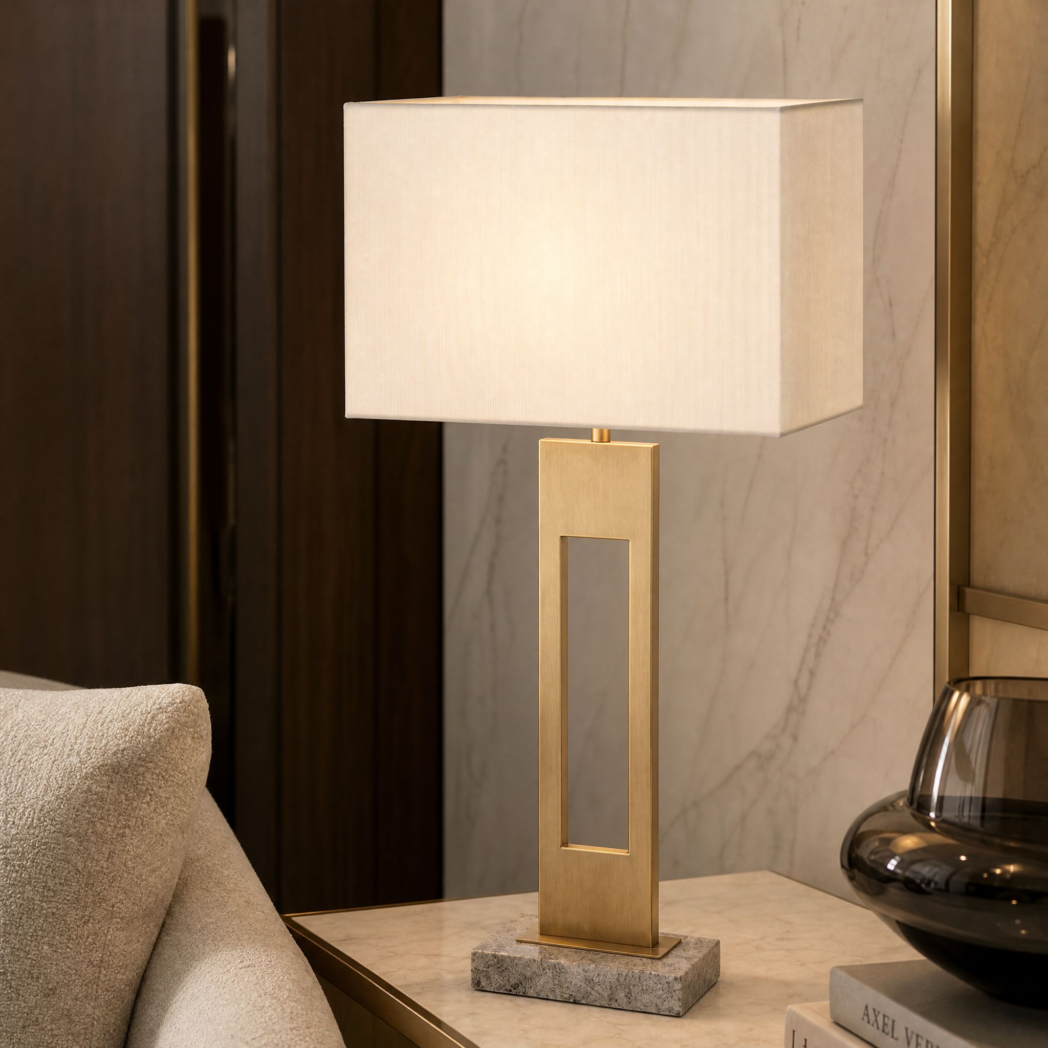 A macro close-up of the Varello table lamp by VORELLI, highlighting the premium contrast between the textured grey marble base and the warm antique brass finish.