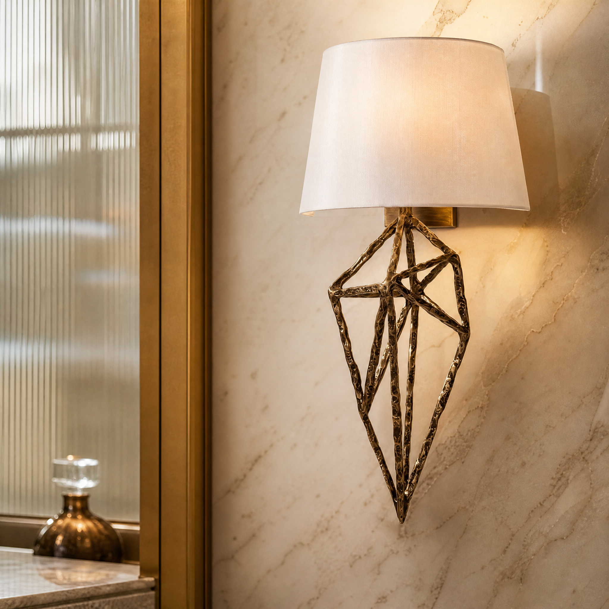 A detailed closeup of the Virella wall light highlighting the intricate sculptural brass frame and textured fabric shade.