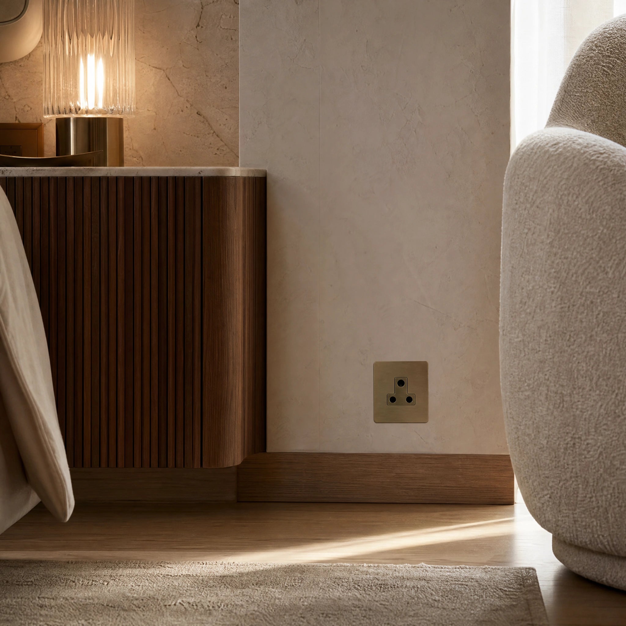 Luxury antique brass 5a socket installed within bespoke bedside joinery or low-level wall beside a luxury seating area in a UHNW interior by VORELLI®.