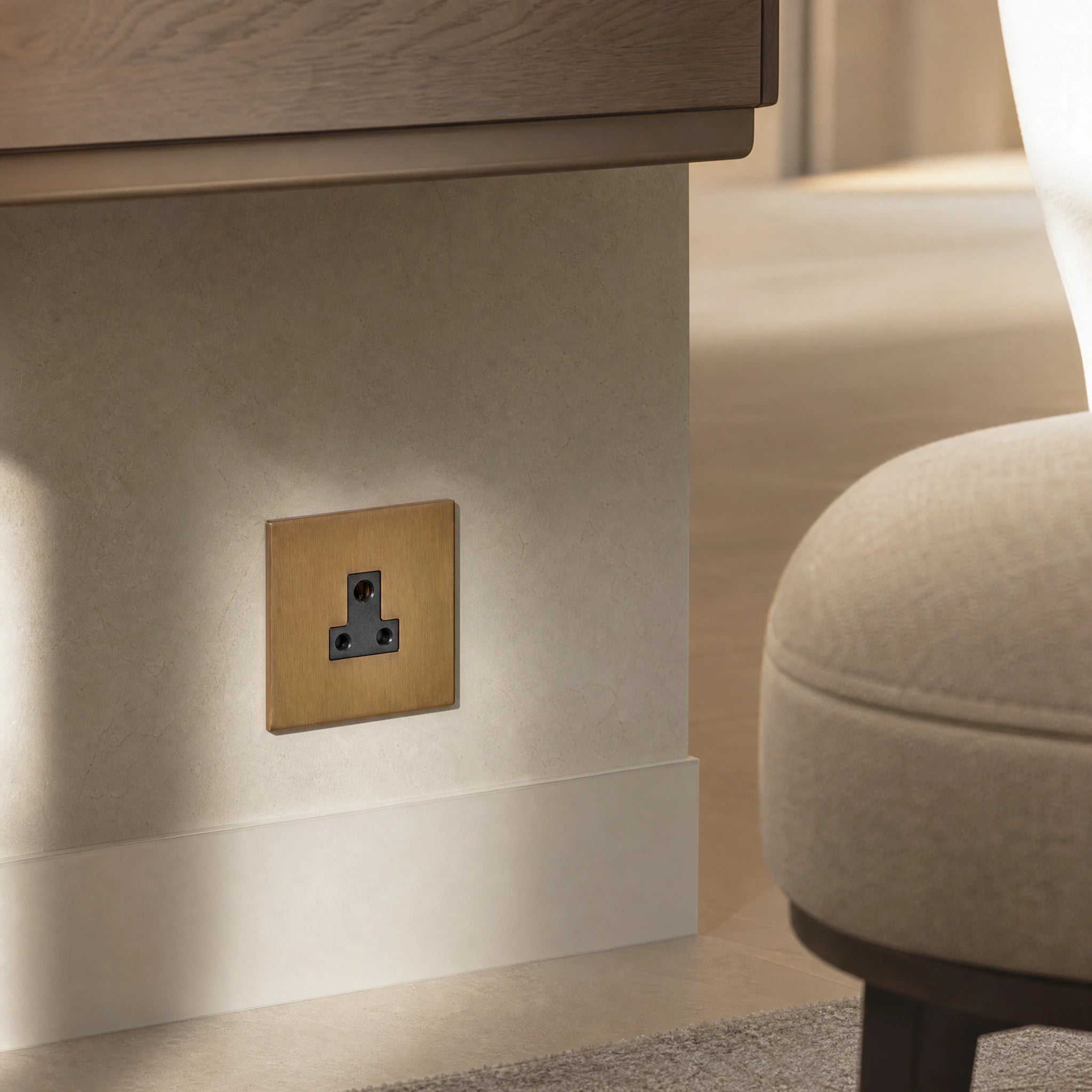 Close-up of a luxury sienna 5a socket installed within bespoke bedside joinery or low-level wall beside a luxury seating area by VORELLI®.