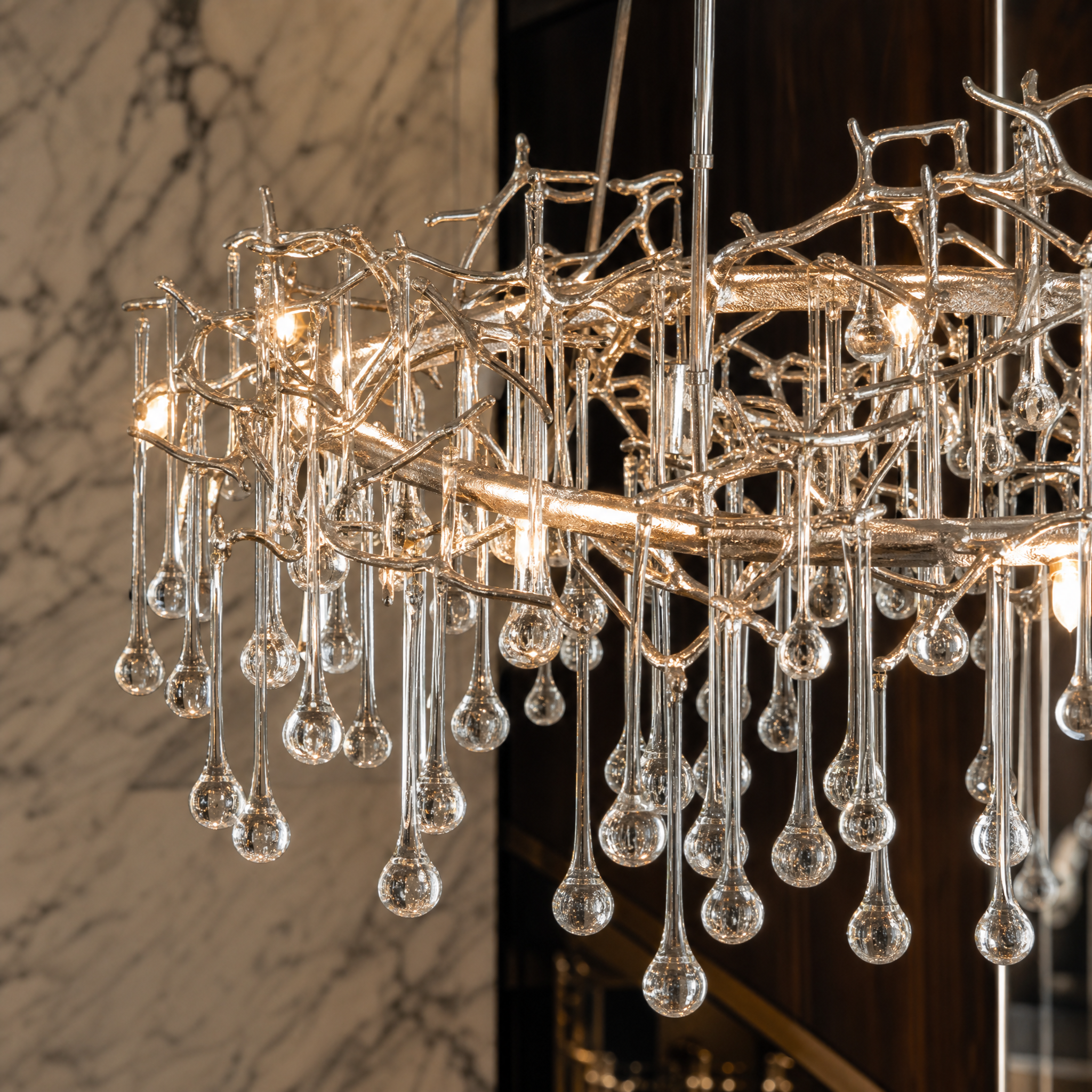 Detailed closeup of the flowing branches and suspended glass droplets of the VORELLI L’Albero d’Oro circular chandelier, showcasing depth and movement.