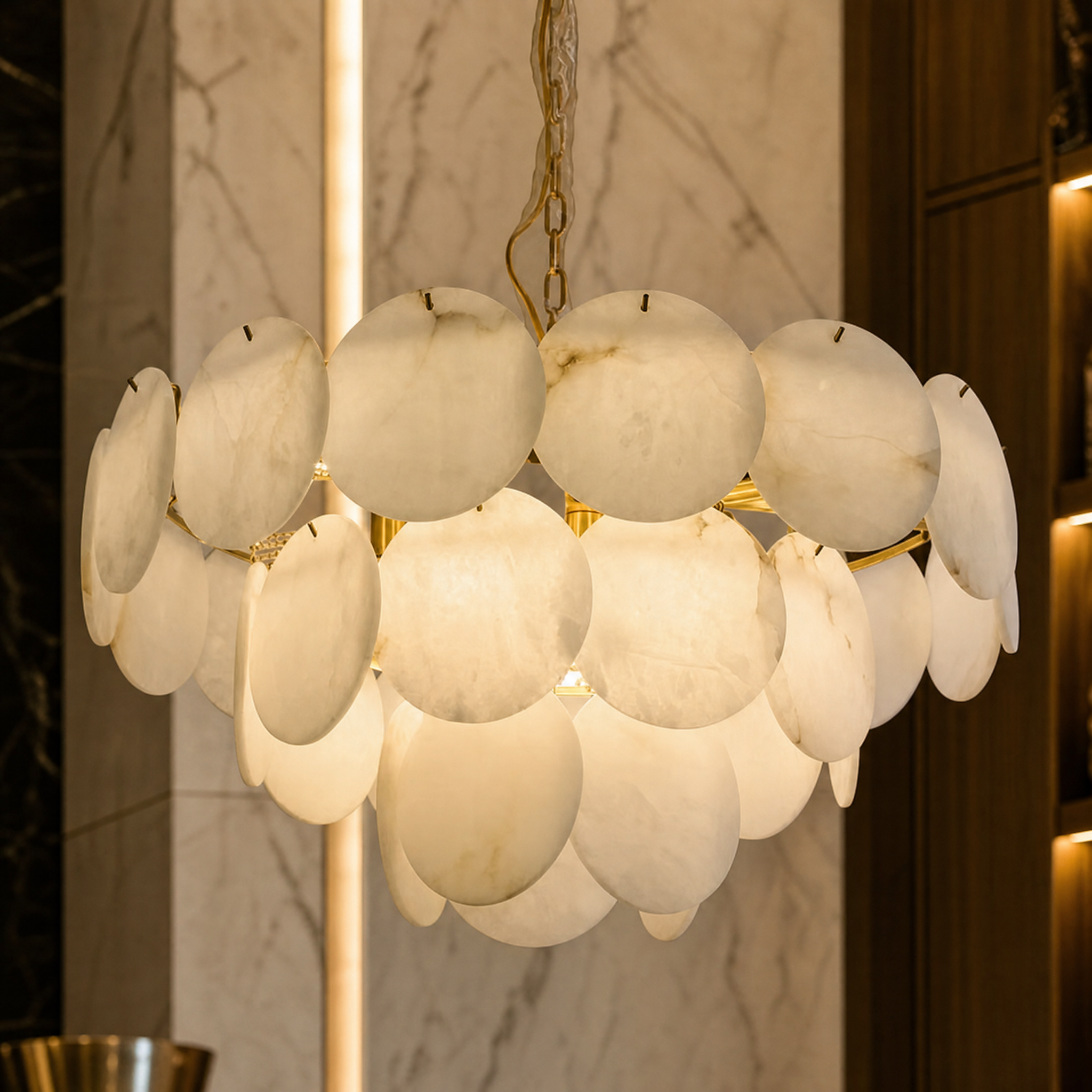 VORELLI Alfonso circular chandelier showcasing the soft illuminating texture of stacked premium marble discs in a beautifully styled luxury interior.
