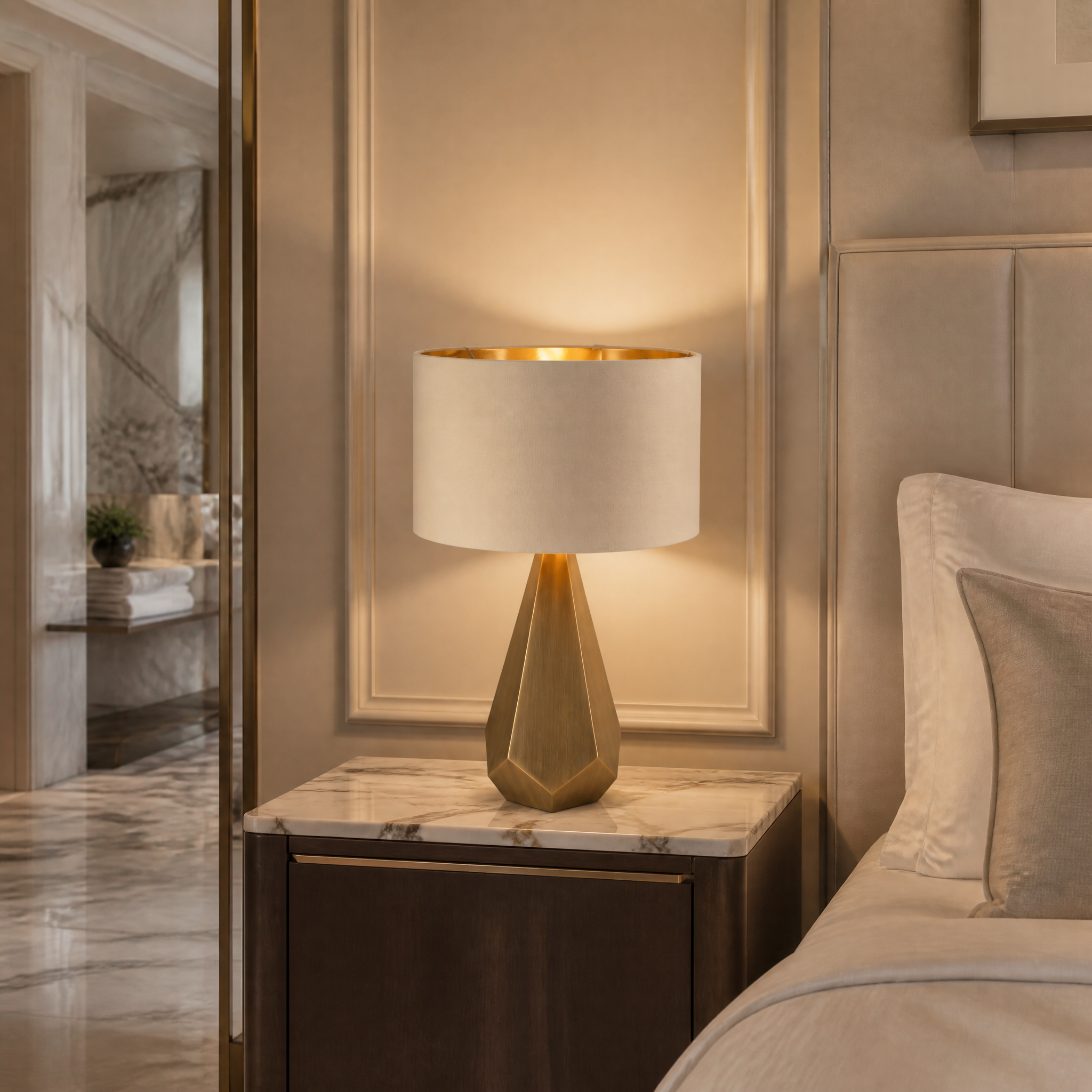VORELLI Arvion architectural brass table lamp illuminating an upscale hotel lounge setting with its sophisticated gold-lined fabric shade.