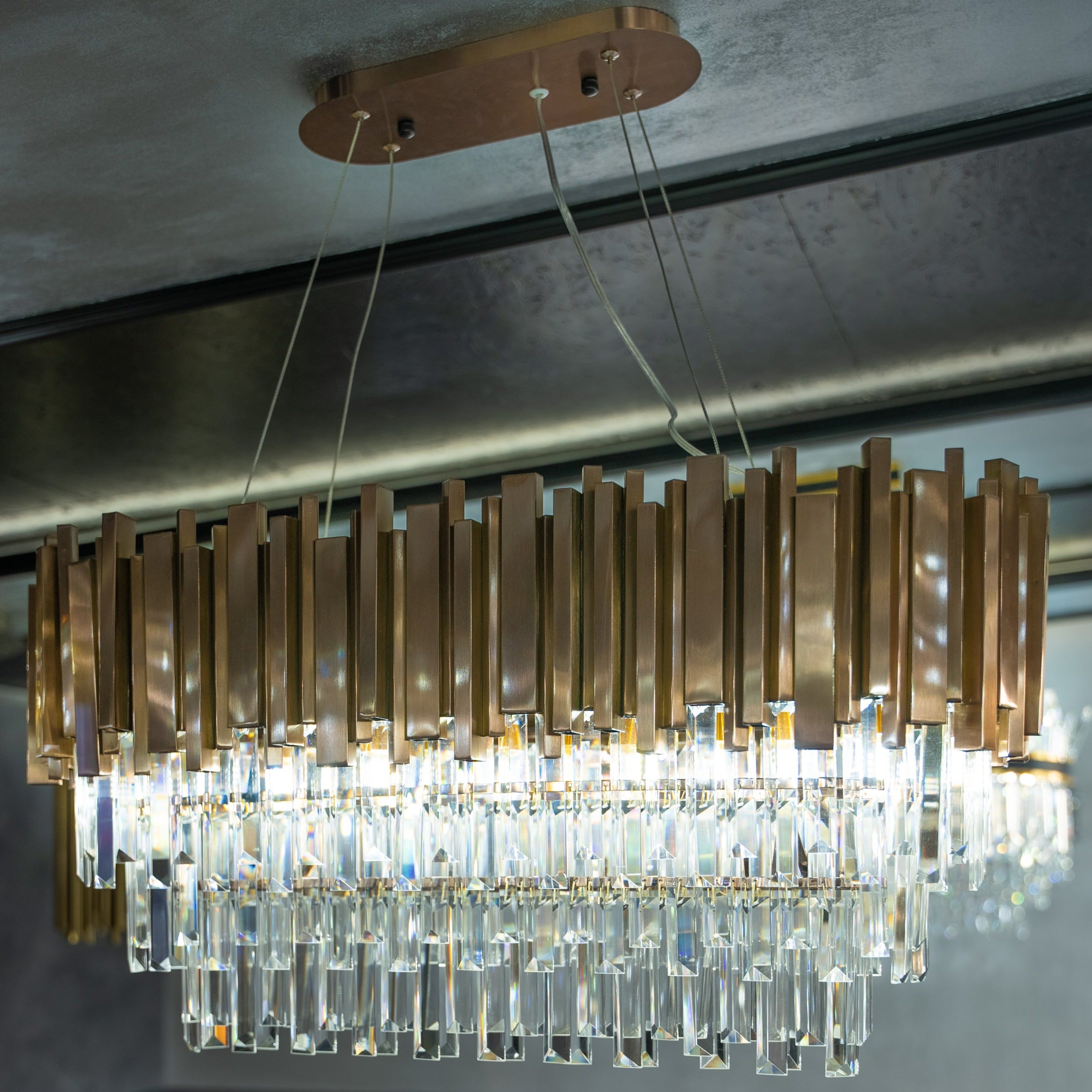 Boeotia Rectangular Chandelier installed in a warm-toned room, showcasing its gold tubular frame and crystal accents.