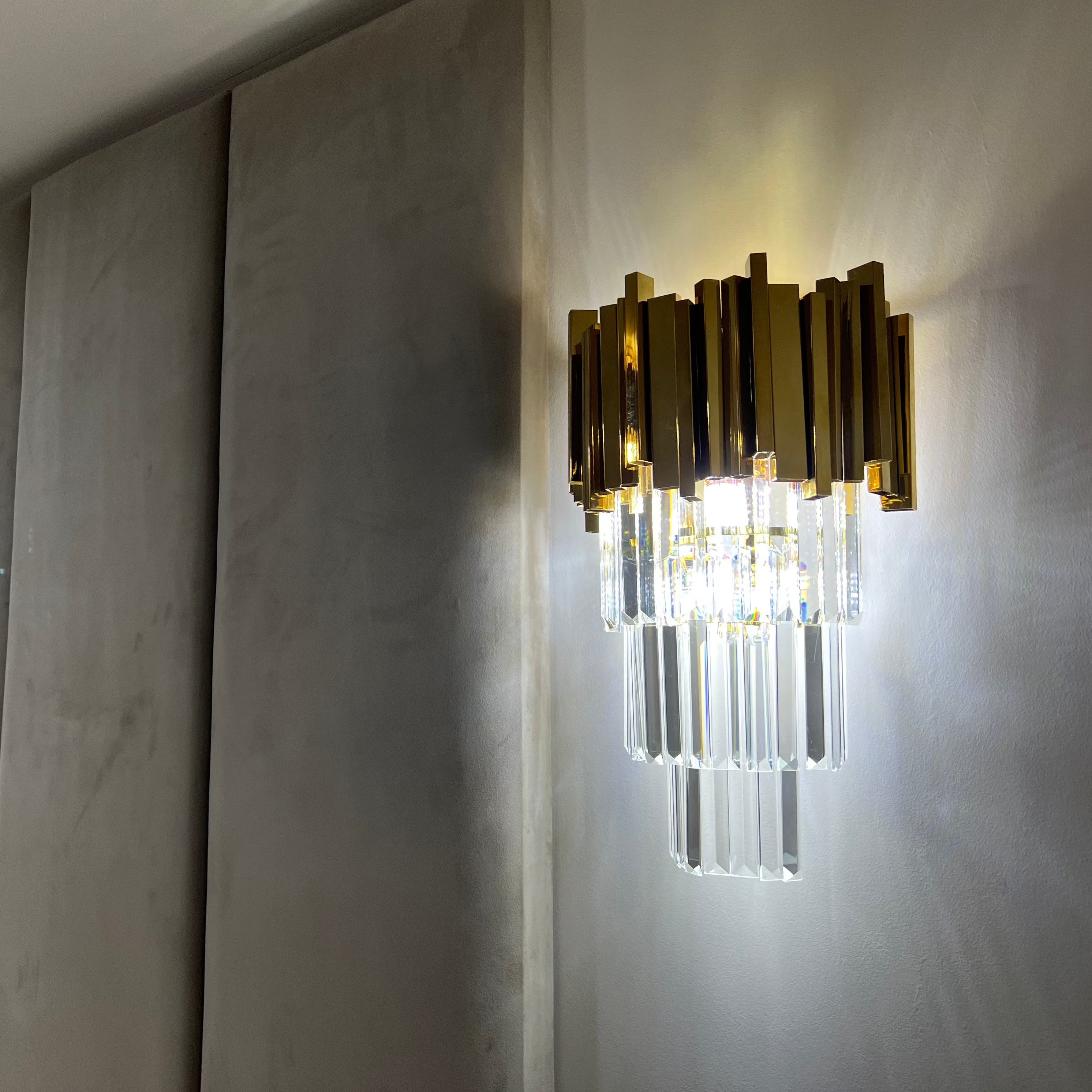 Close-up of the Boeotia Wall Light highlighting illuminated crystal bars and gold cuboid tubing.