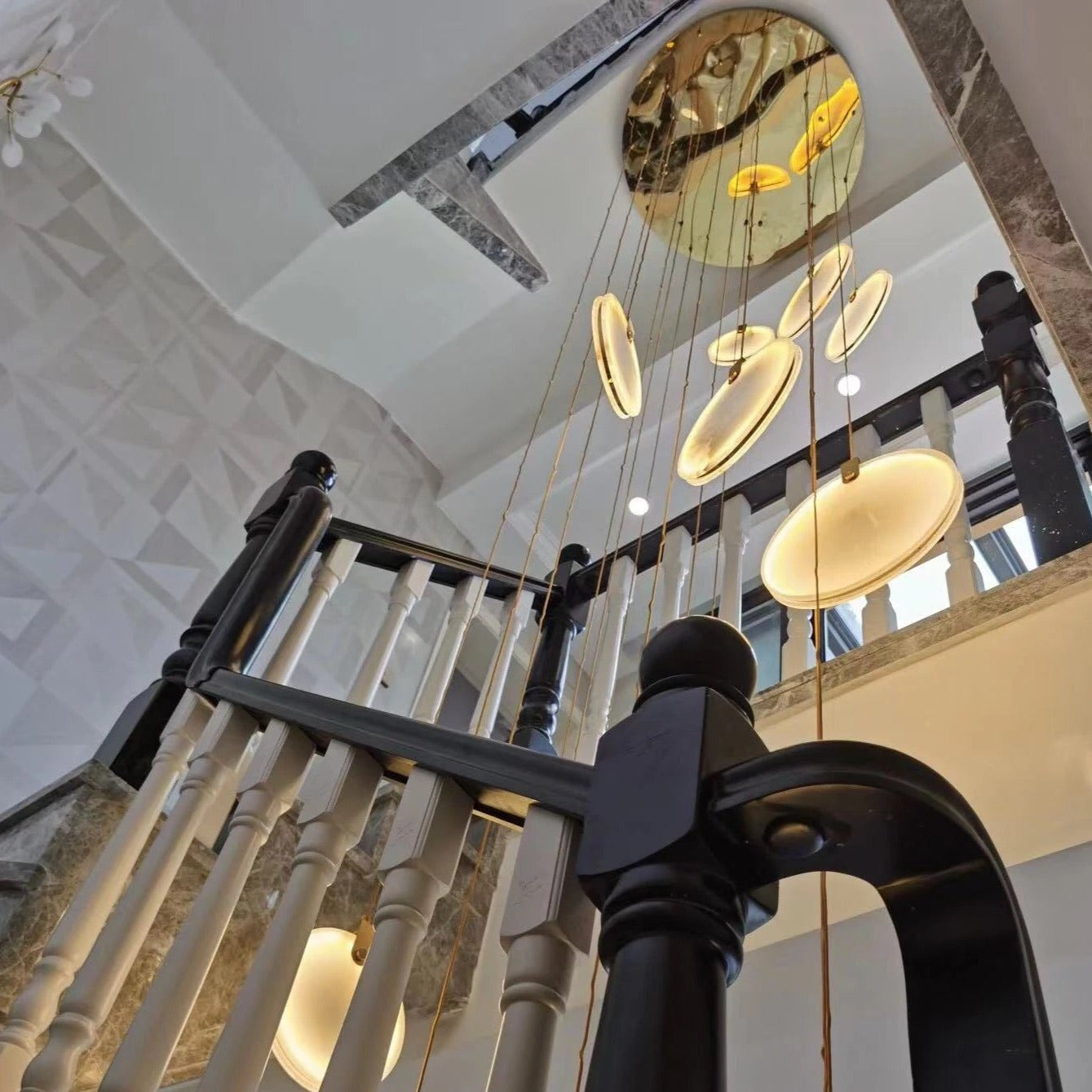 Side profile of cascading Calacatta marble pendants creating a luxurious stairwell focal point.