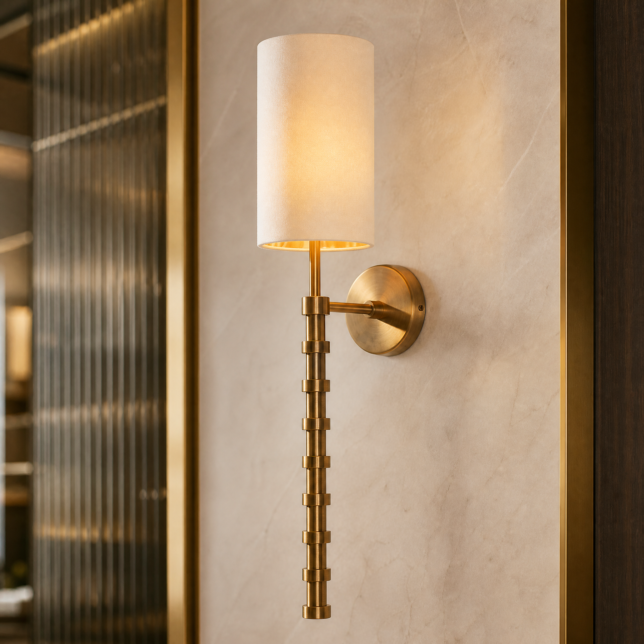 A detailed close-up of the VORELLI Calvane wall light, highlighting the rich texture of the refined fabric shade and the subtle detailing of the warm antique brass finish.