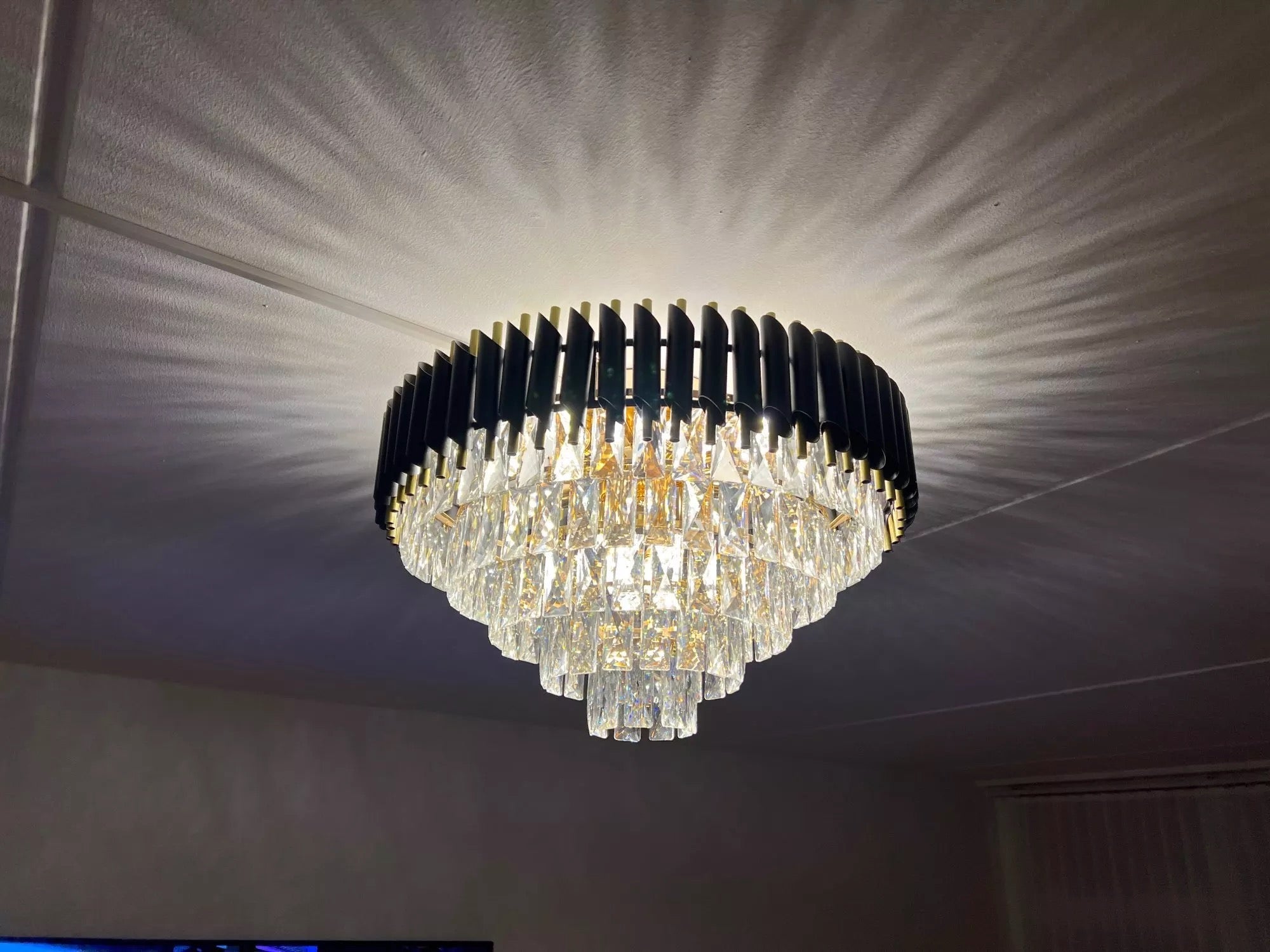 Statement crystal ceiling chandelier by VORELLI® illuminating a contemporary living space with refined ambient glow.