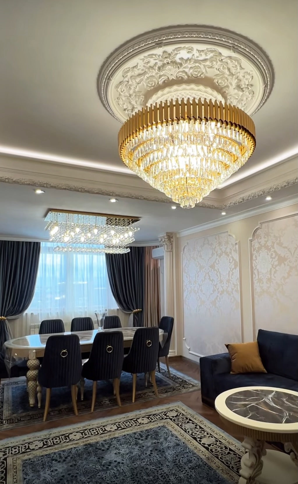 Elegant crystal ceiling chandelier by VORELLI® suspended above a luxury dining room interior.