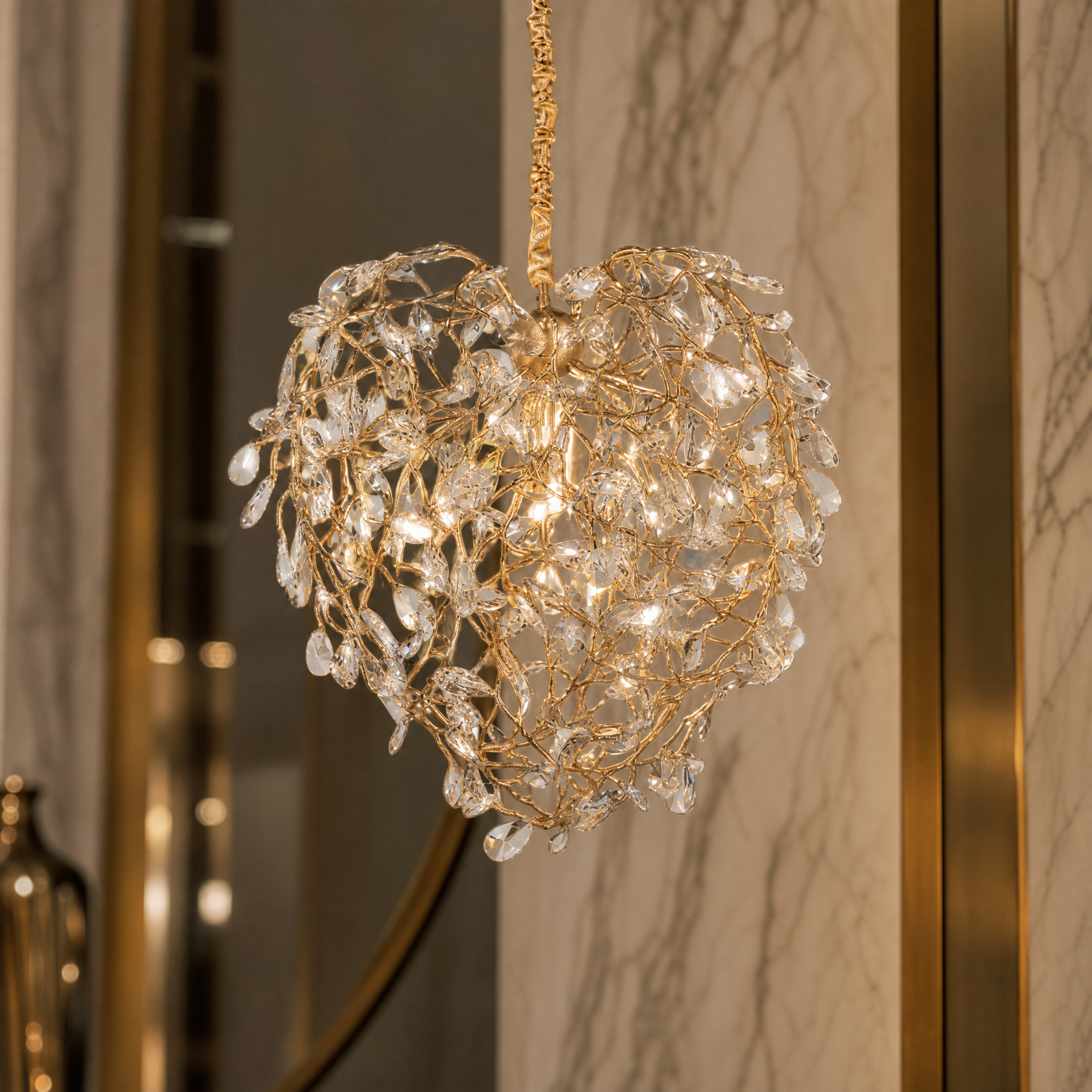 A detailed closeup of the VORELLI Entwine Heart Pendant Light showing the intricate entwined gold branches and diamond-cut crystal drops.