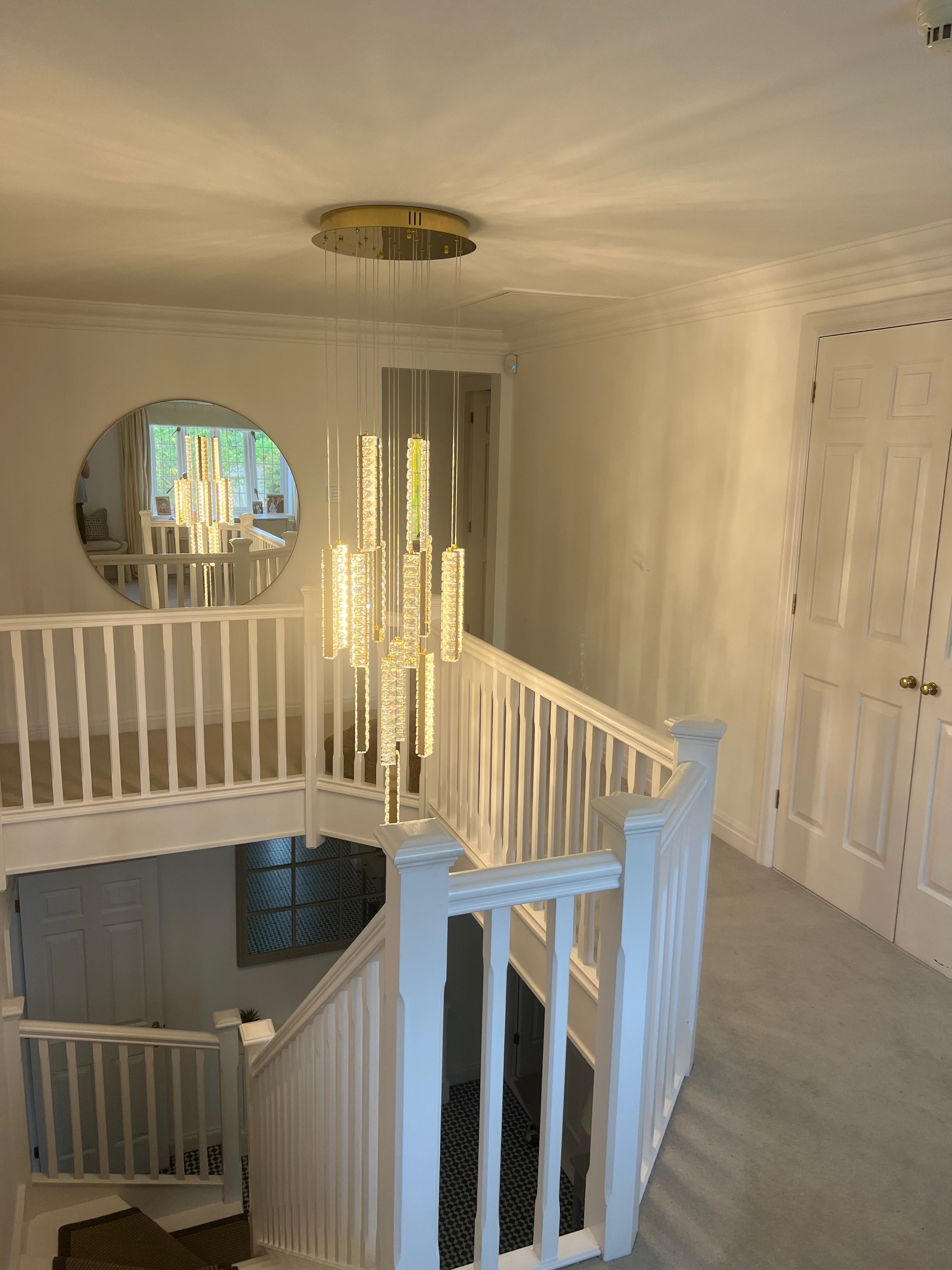 Modern cascading staircase chandelier illuminating a double height interior with refined crystal elegance