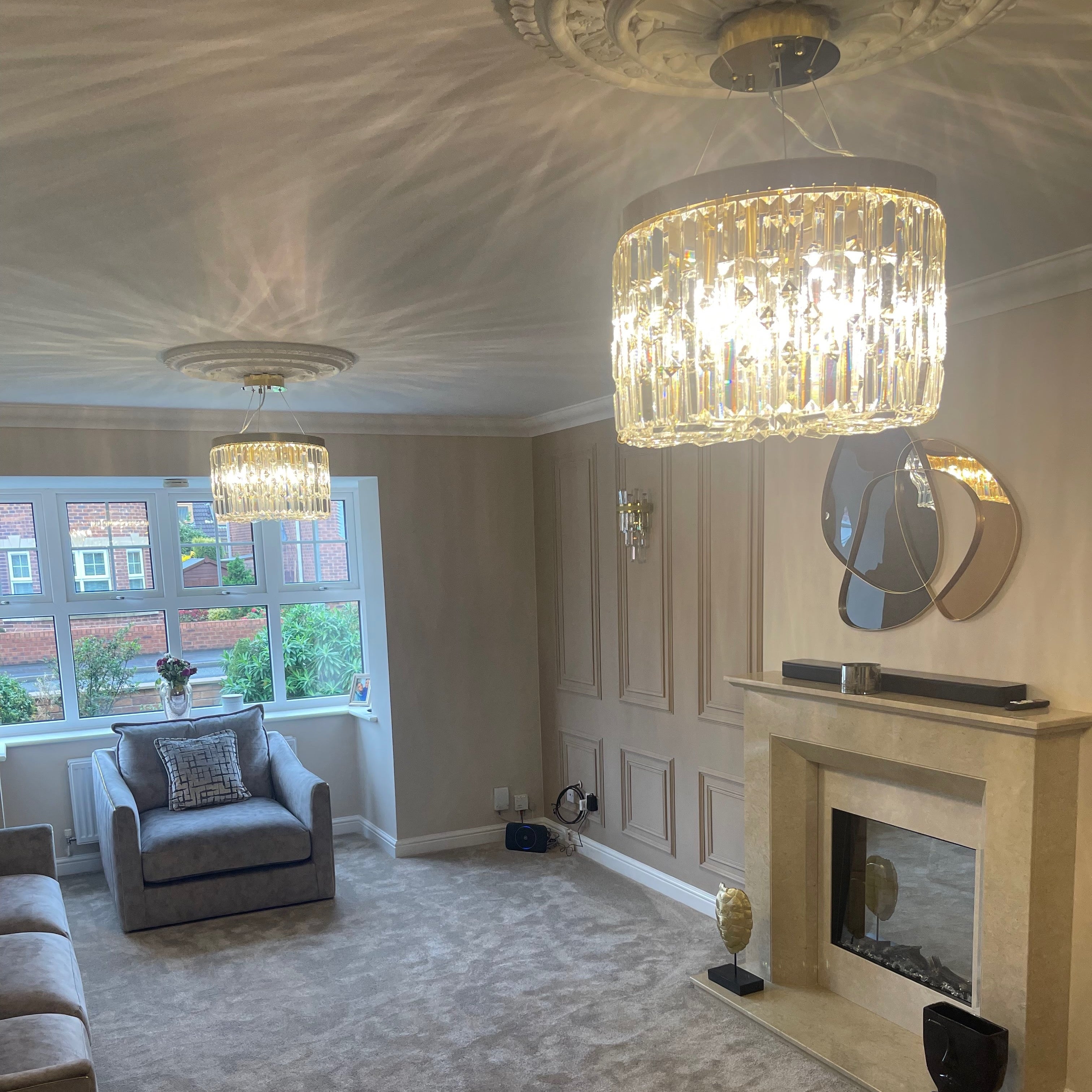 Circular crystal chandelier positioned above fireplace within a sophisticated lounge interior