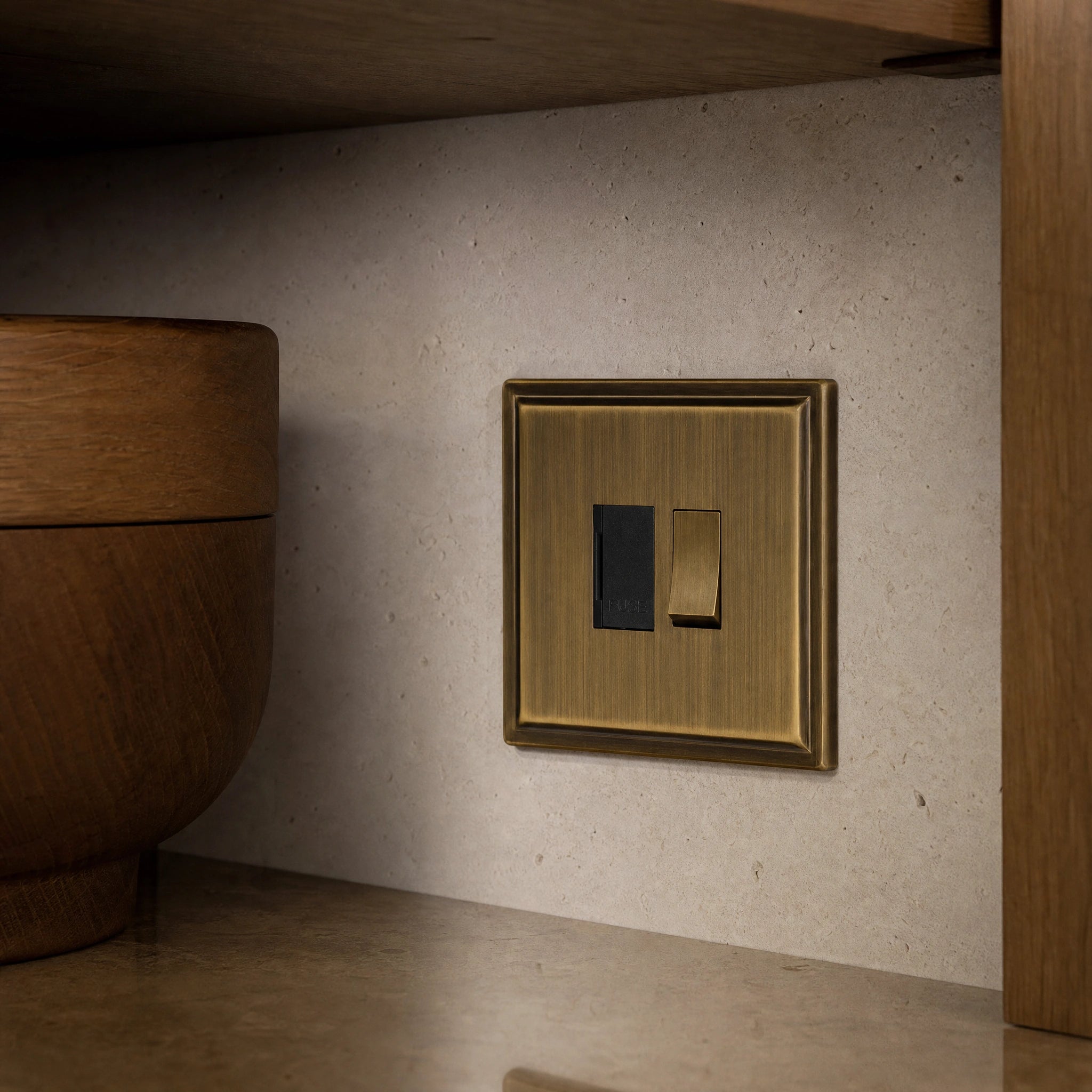 Close-up of a luxury antique brass fused spur installed within discreet below-cabinet utility or kitchen appliance zone in a high-end residence by VORELLI®.