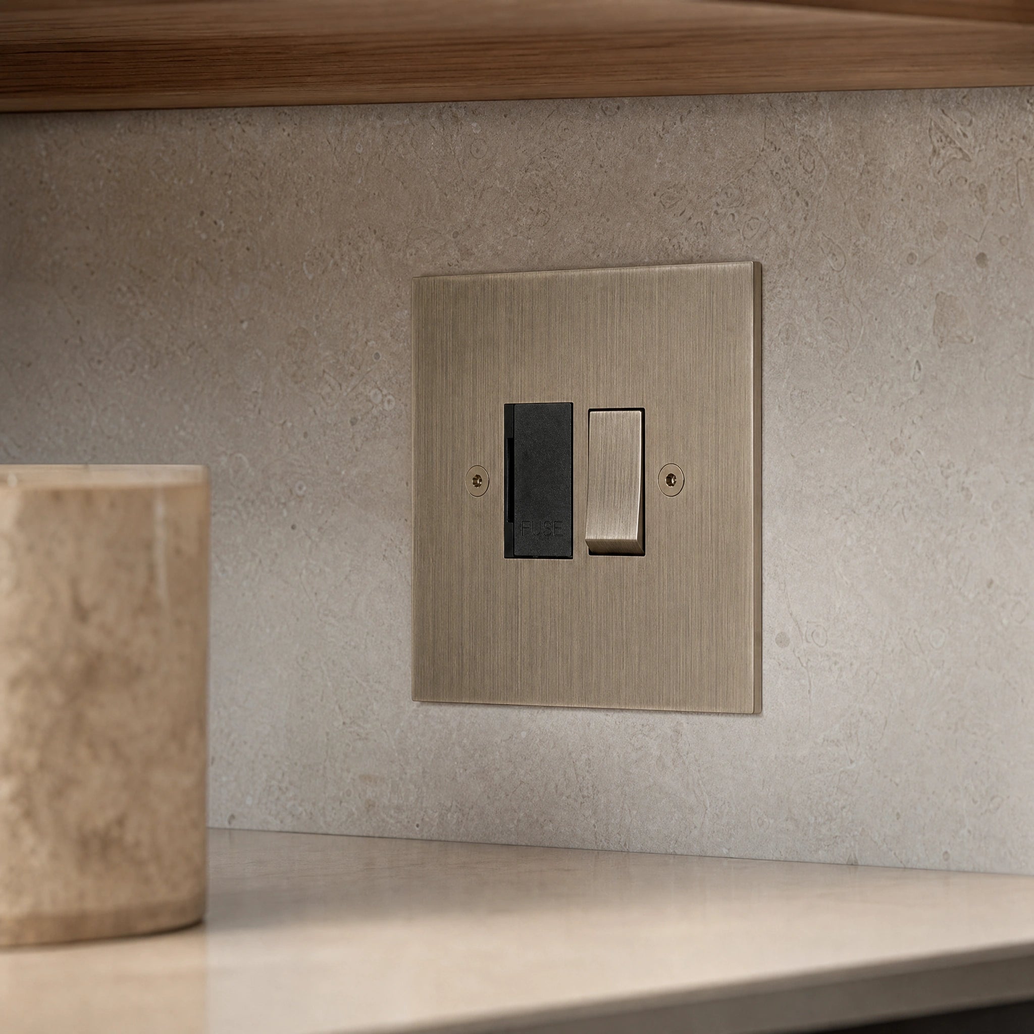 Close-up of a luxury antique brass fused spur installed within discreet below-cabinet utility or kitchen appliance zone in a high-end residence by VORELLI®.