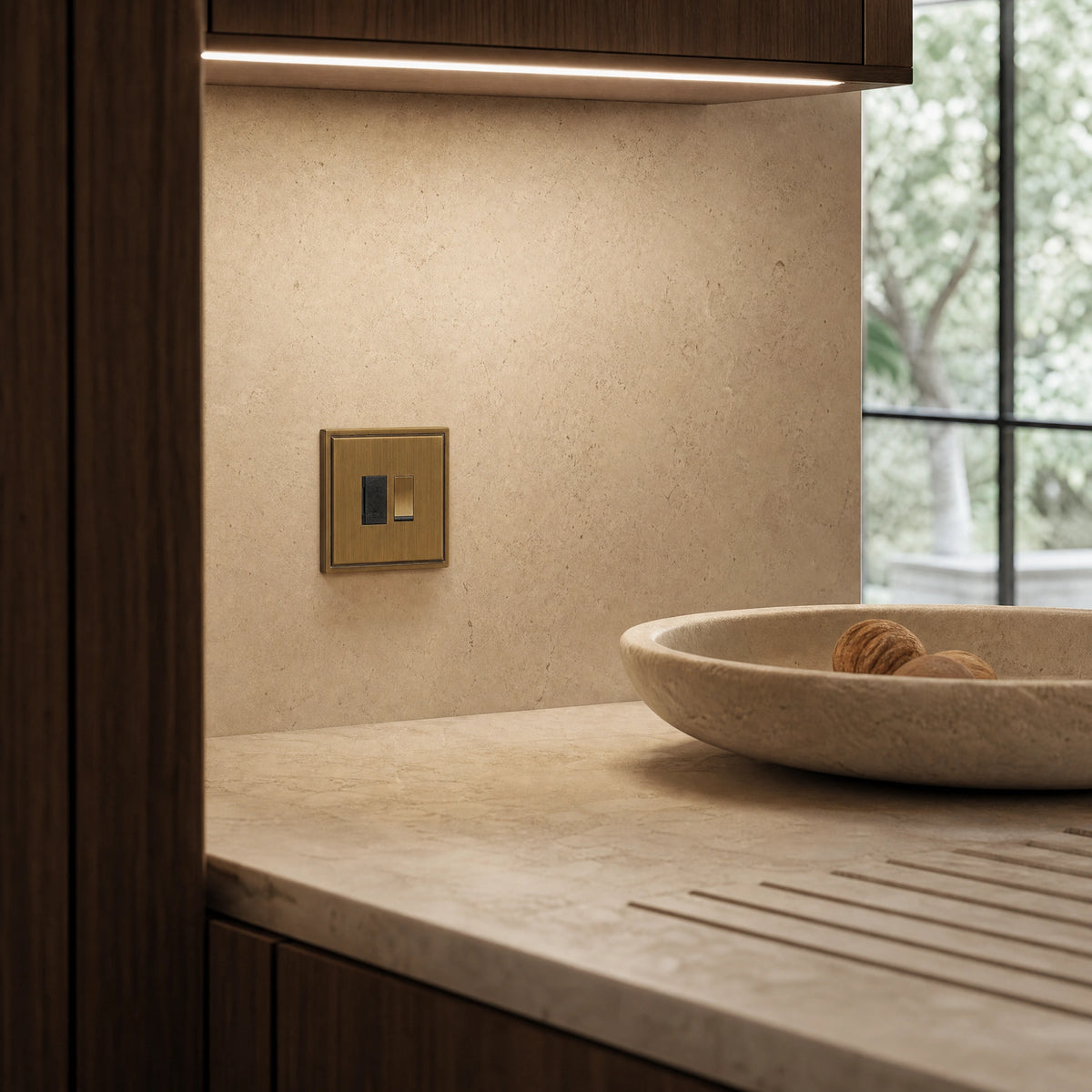 Luxury antique brass fused spur installed within discreet below-cabinet utility or kitchen appliance zone in a high-end residence in a UHNW interior by VORELLI®.